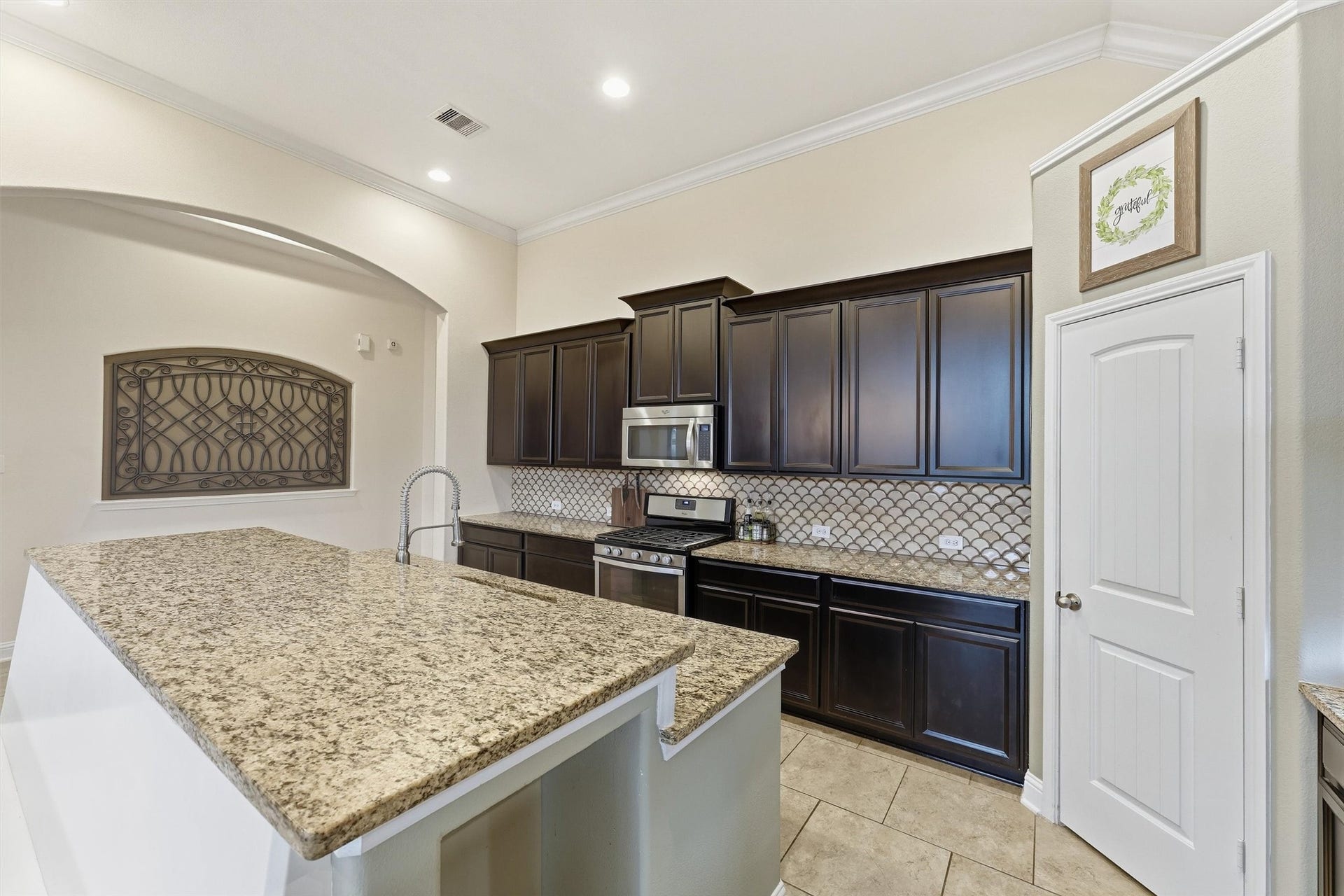 1413 Silver Rings Court, Pearland, TX 77581 Elegant kitchen with dark cabinetry, granite countertops, and a stylish tile backsplash, offering modern appliances and ample storage.