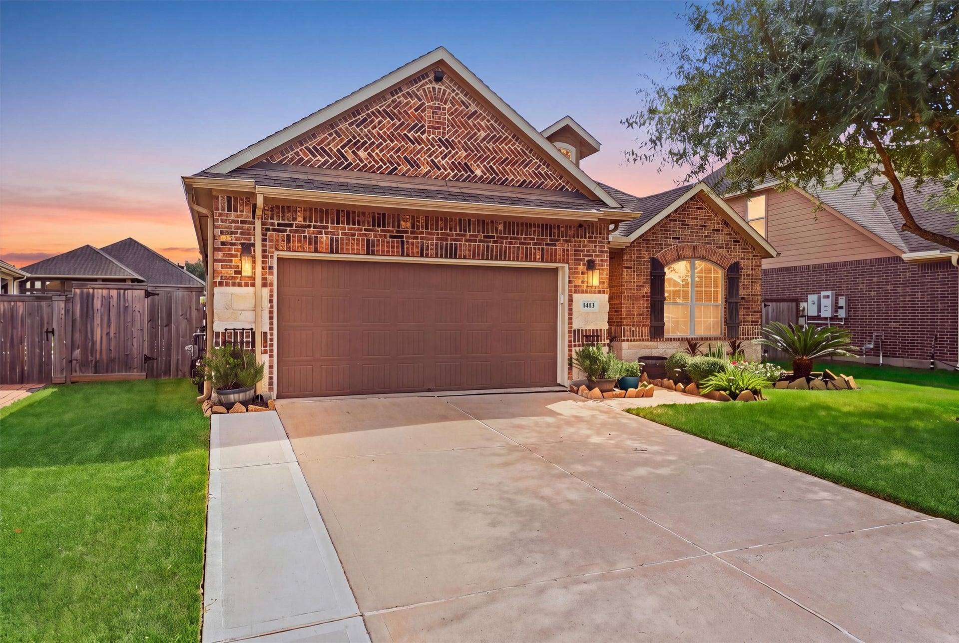 1413 Silver Rings Court, Pearland, TX 77581 Charming brick home with a spacious two-car garage, elegant arched windows, and well-maintained landscaping, set against a beautiful sunrise backdrop.