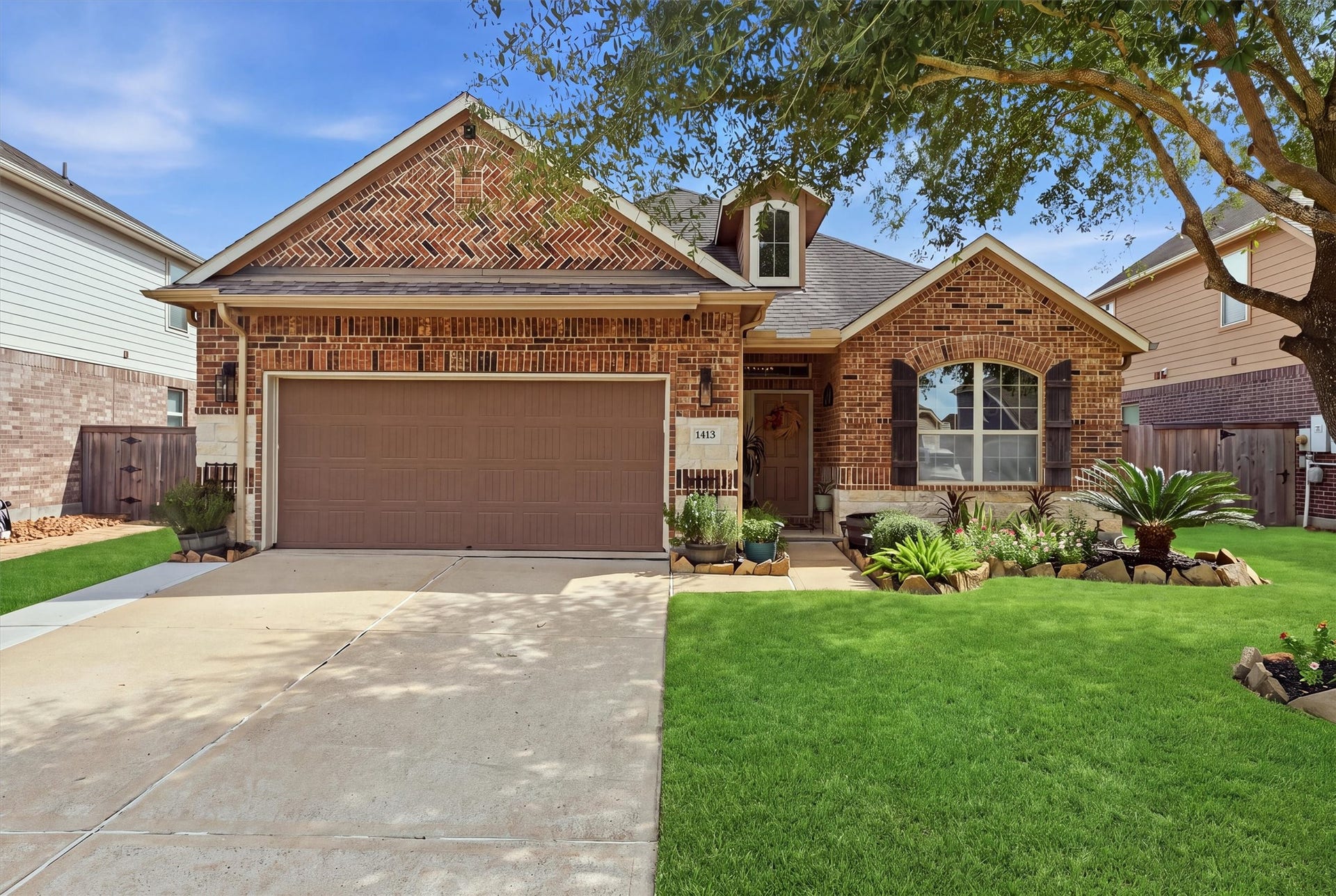 1413 Silver Rings Court, Pearland, TX 77581 Charming brick home with a spacious two-car garage and beautifully landscaped front yard, accented by lush greenery and mature tree.