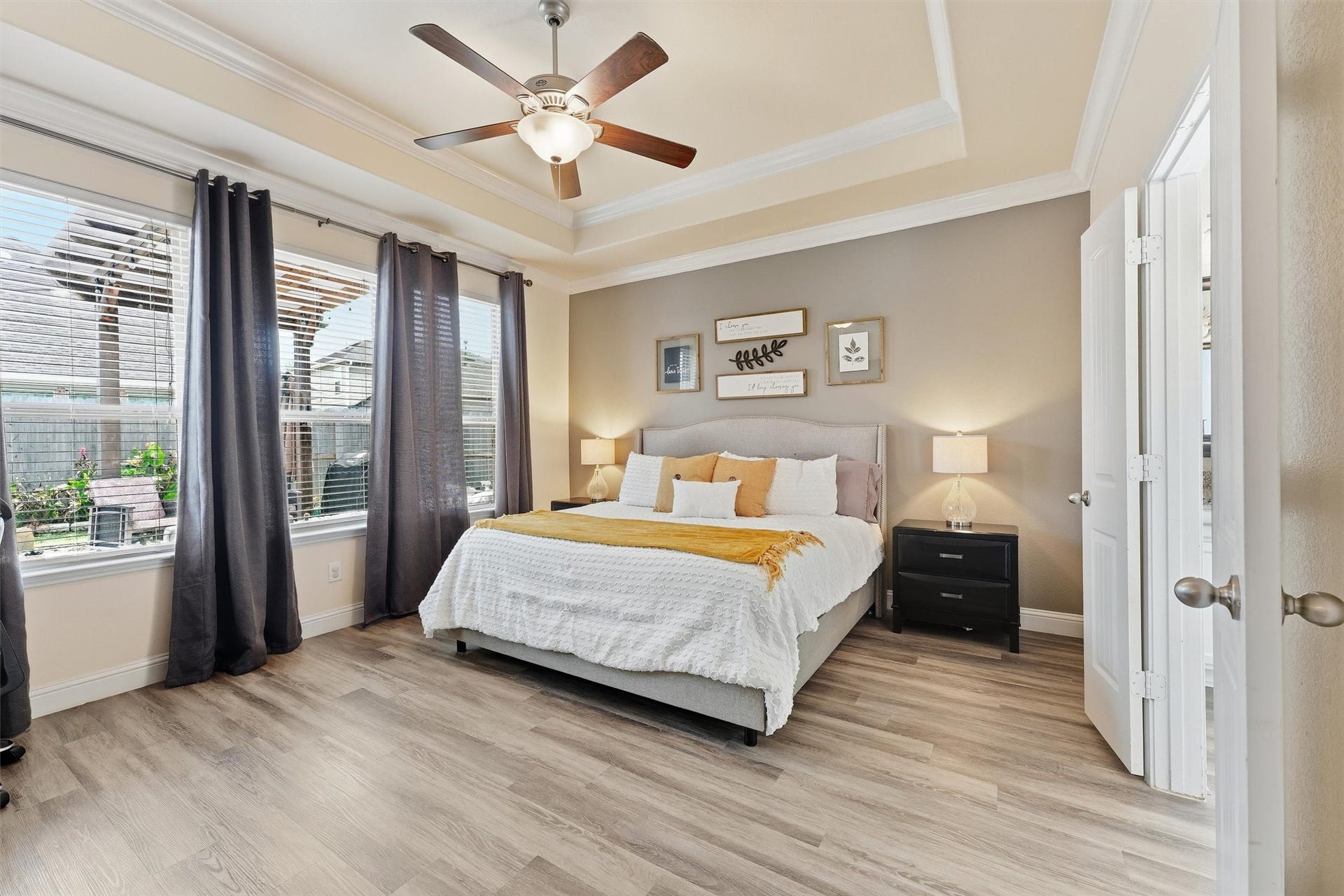 1413 Silver Rings Court, Pearland, TX 77581 Spacious and inviting primary bedroom featuring large windows for ample natural light, a stylish tray ceiling with a fan, and modern flooring.