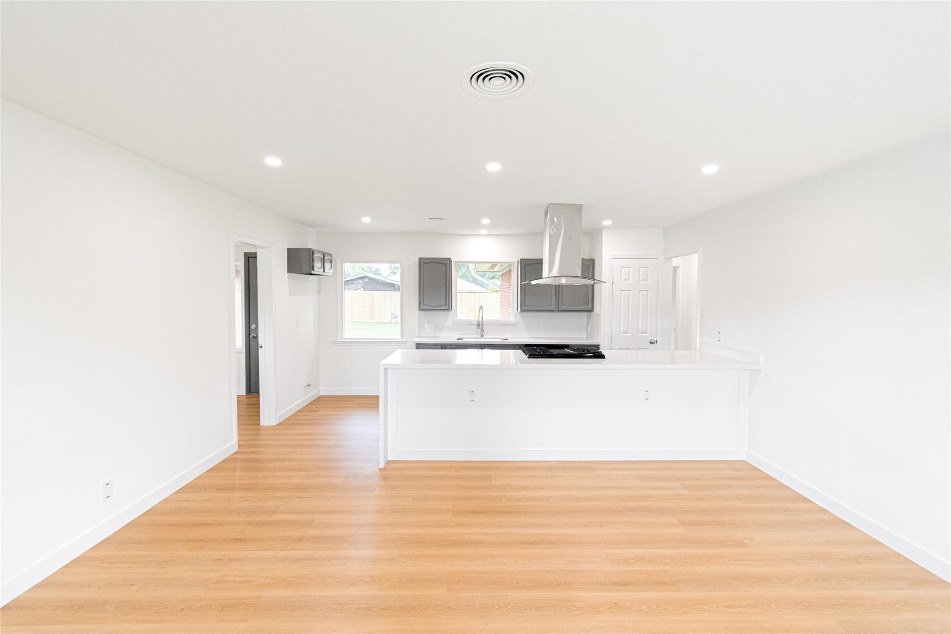 2730 Knotty Oaks Trail, Houston, TX 77045 Discover a bright, open-concept kitchen and living area with sleek white cabinetry, modern appliances, and warm wood flooring, perfect for stylish living.