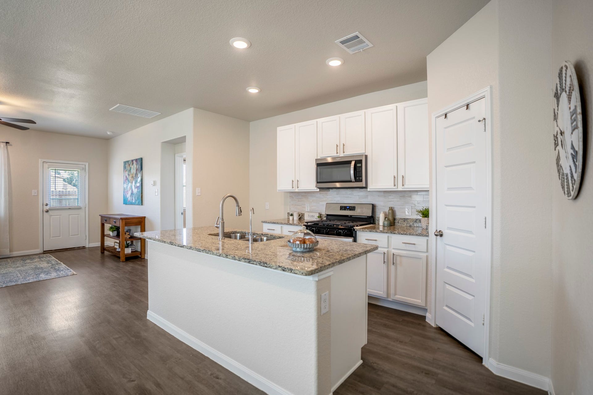 2355 Mount Locke Path, Conroe, TX 77301 From this angle, the kitchen feels even more connected to the rest of the first floor, with the island stretching toward the dining and living spaces on the left. The pantry sits just beyond the kitchen on the right, while the updated backsplash, cabinet hardware, granite counters, and stainless appliances keep the workspace feeling polished and practical.