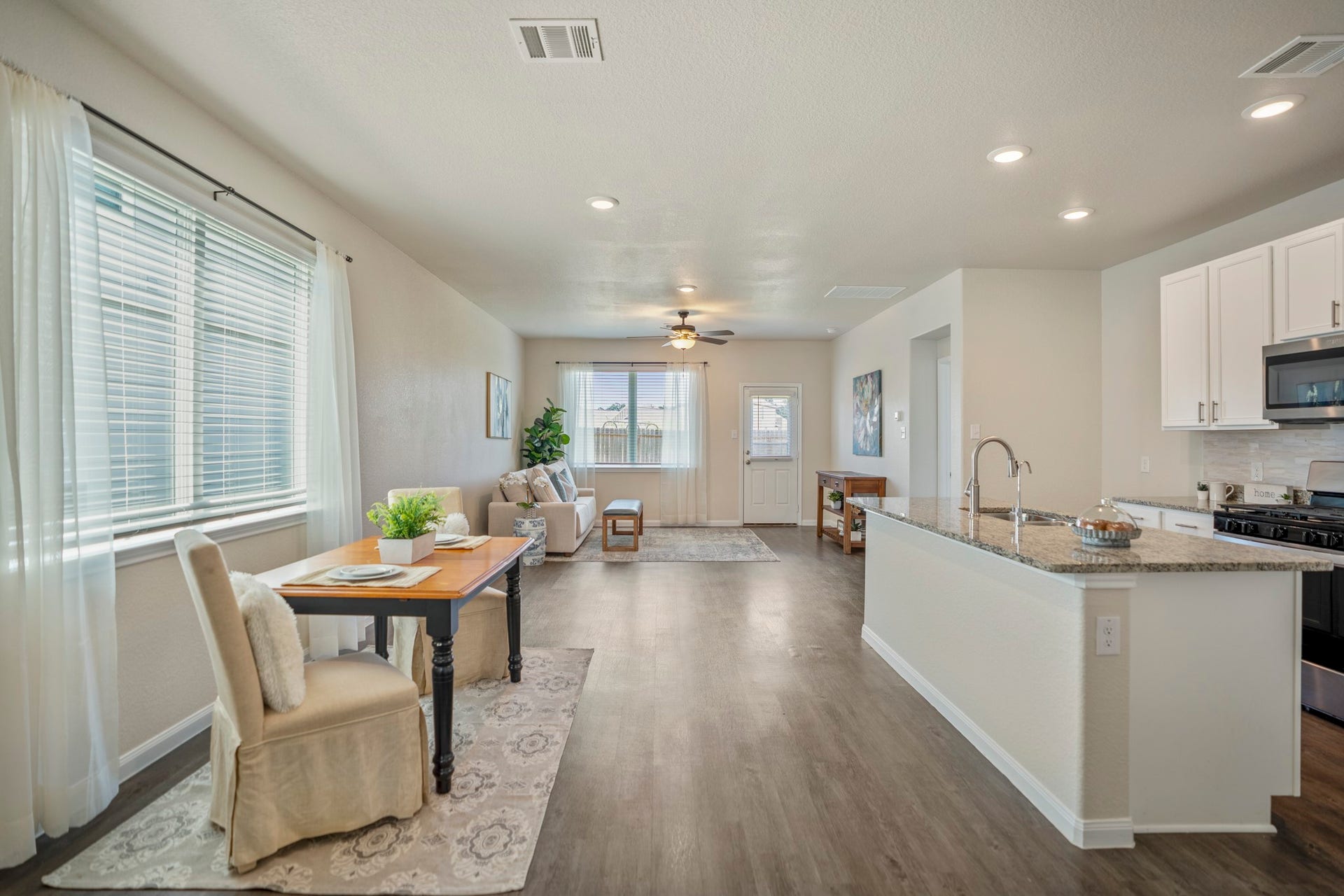 2355 Mount Locke Path, Conroe, TX 77301 Continuing into the main living area, the dining space opens up along the left with a row of windows bringing in natural light, while the kitchen runs along the right with the island extending toward the living room. Straight ahead, the living room continues toward the back of the home, creating an easy connection between cooking, dining, and relaxing.