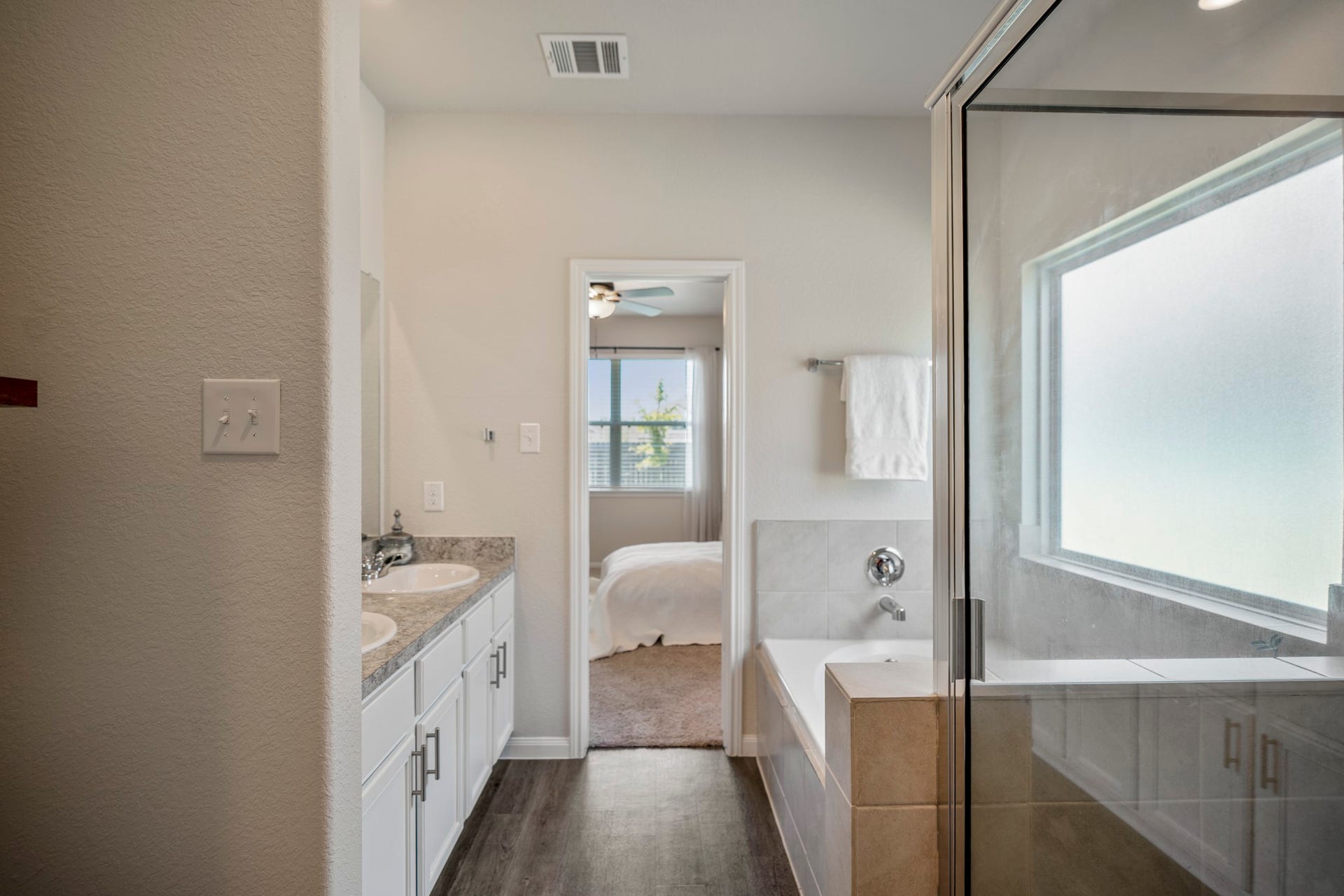 2355 Mount Locke Path, Conroe, TX 77301 Looking back through the primary bath, this angle ties the suite together with the vanity on the left, soaking tub and the glass-enclosed shower on the right. The doorway ahead leads back into the primary bedroom, completing the easy flow through the suite.