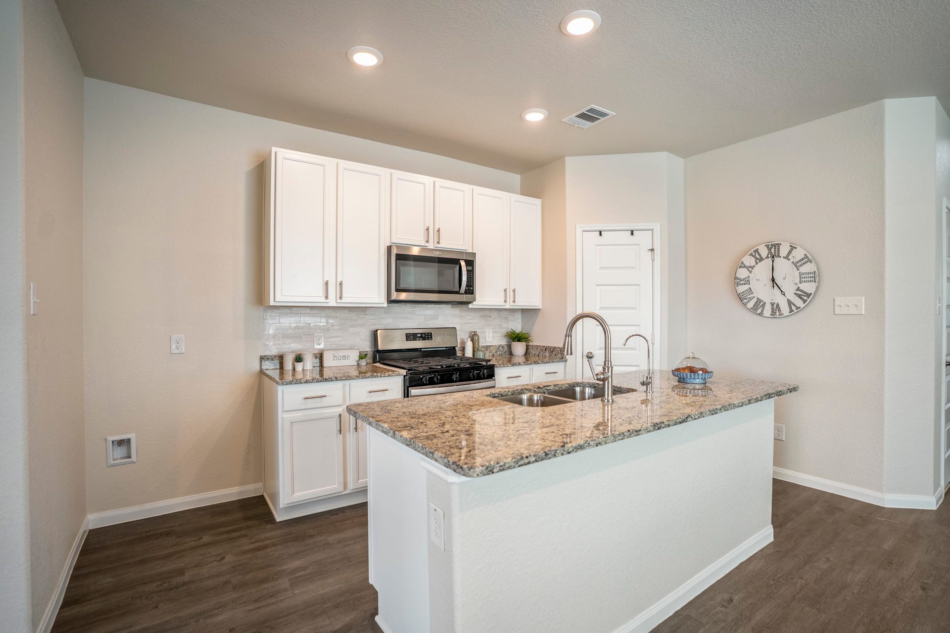 2355 Mount Locke Path, Conroe, TX 77301 Moving into the kitchen, the granite-topped island brings the sink right into the center of the action, complete with a separate reverse-osmosis faucet for filtered drinking water. Updated cabinet hardware and backsplash give the space a more custom feel alongside the stainless microwave and gas range, while the pantry door sits just beyond the island for easy access during meal prep.