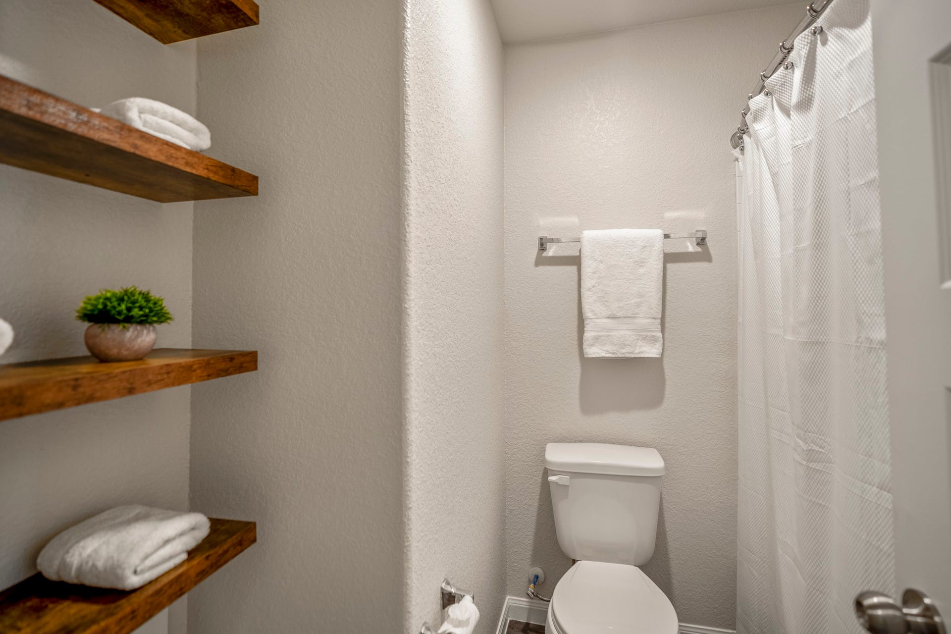 2355 Mount Locke Path, Conroe, TX 77301 Turning deeper into the upstairs full bath, the tub and shower sit along the right with the toilet centered ahead, while open shelving on the left adds easy-access storage for towels and bath essentials. Its a practical setup just steps from the gameroom and all three secondary bedrooms.