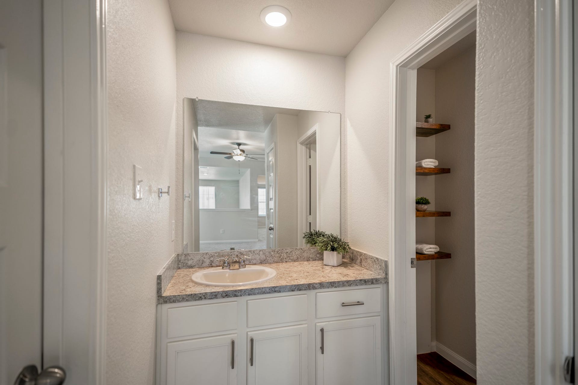 2355 Mount Locke Path, Conroe, TX 77301 Stepping into the upstairs full bath, the vanity sits straight ahead with cabinet storage below, while open shelving along the right adds extra room for towels and everyday essentials. The door on the left leads to the utility room.