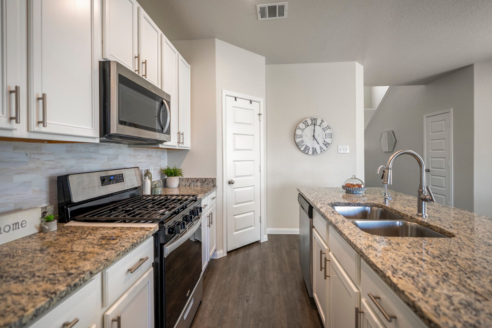2355 Mount Locke Path, Conroe, TX 77301 Looking down the length of the kitchen, this angle shows just how easy the space is to work in, with cabinetry and Whirlpool stainless appliances along the left and the granite-topped island running parallel on the right. The 5-burner gas range gives you a little extra cooking flexibility, while the microwave above keeps the setup streamlined and everything within easy reach.
