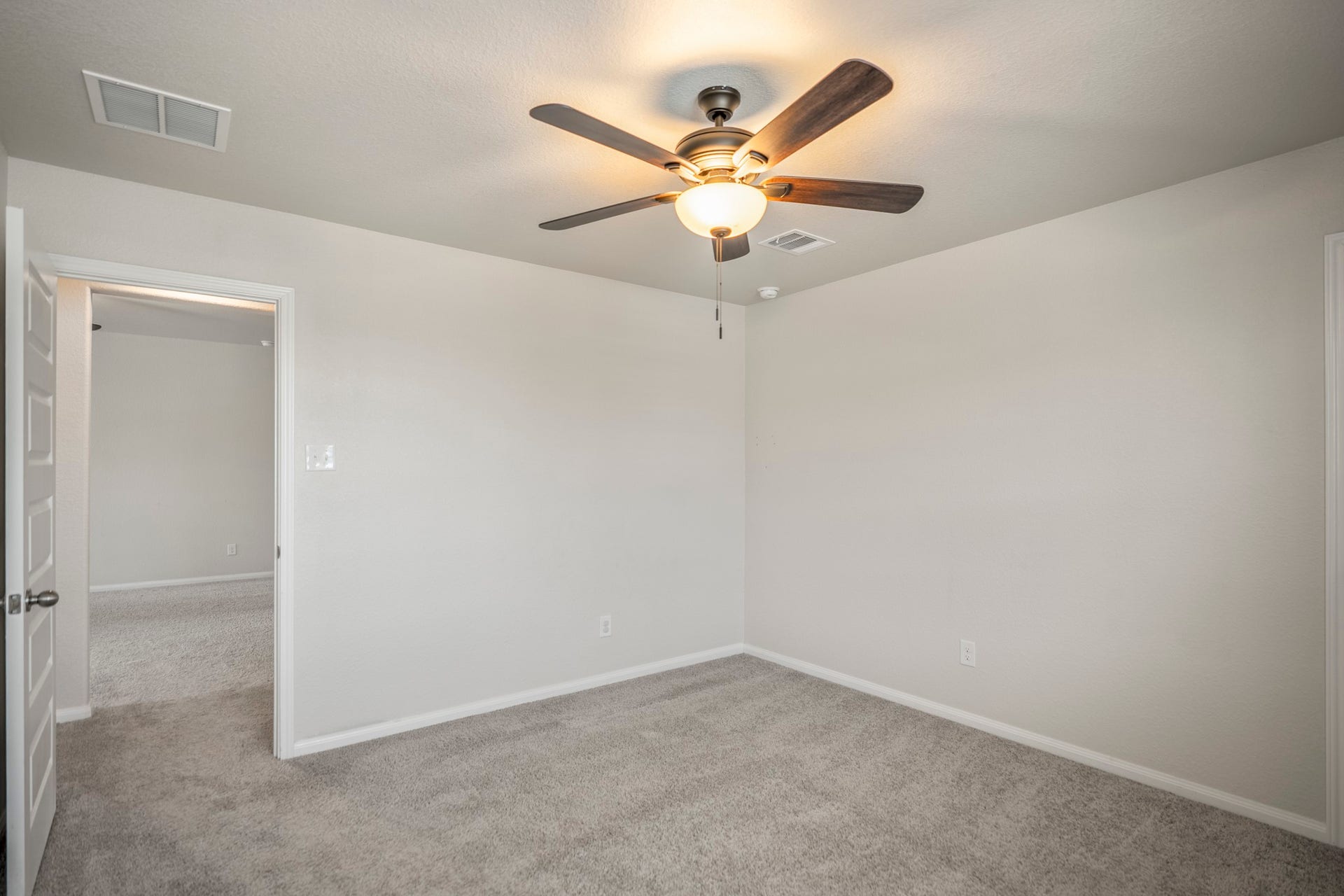 2355 Mount Locke Path, Conroe, TX 77301 Turning within the second bedroom, this angle shows the rooms open floor area and the doorway on the left leading back out to the gameroom. The ceiling fan stays centered overhead, while the neutral finishes keep the space feeling light and easy to personalize.