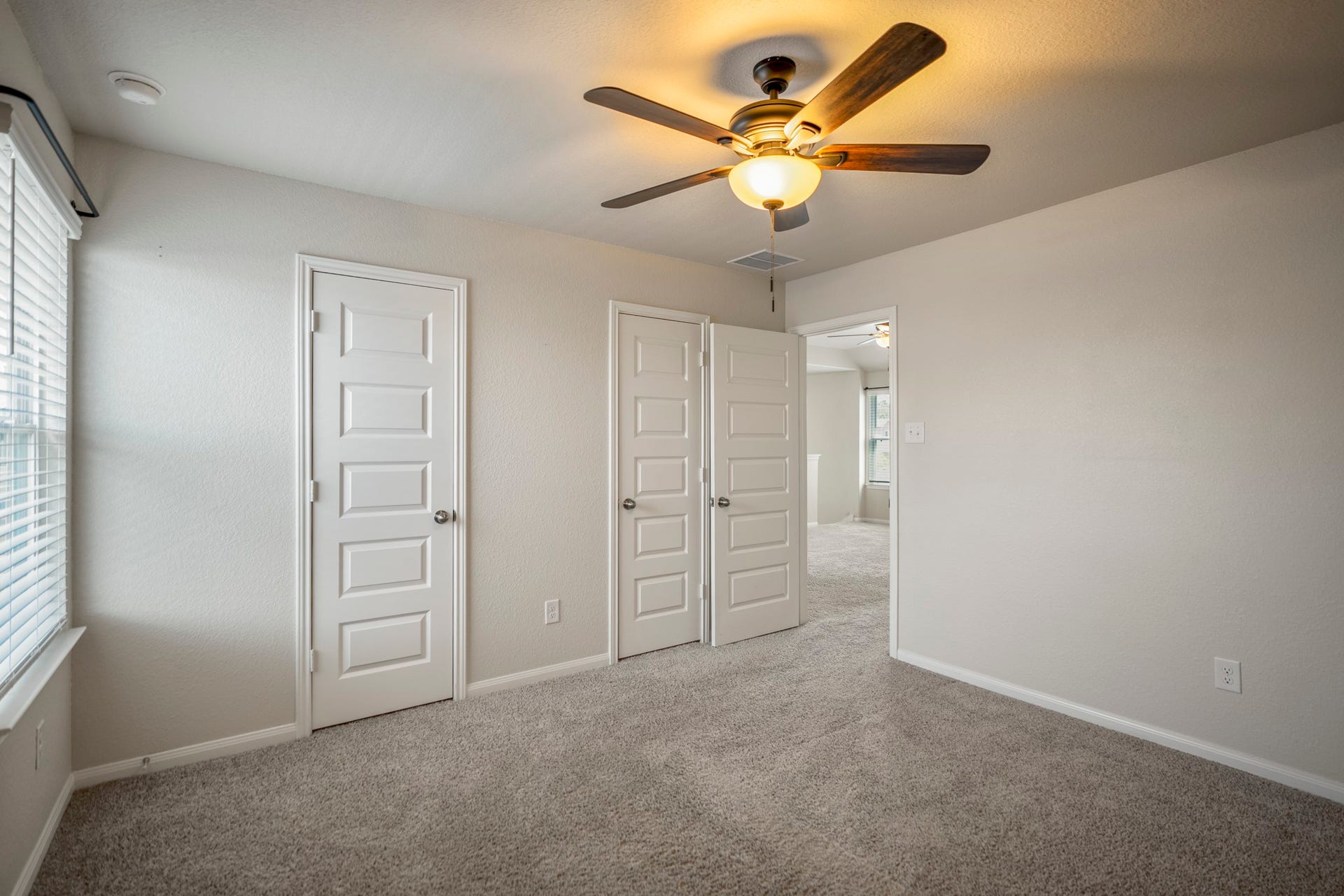 2355 Mount Locke Path, Conroe, TX 77301 Turning within the fourth bedroom, this angle gives a better sense of the rooms layout and open floor area. The pair of closet doors comes fully into view ahead, emphasizing just how much storage this secondary bedroom offers, while the ceiling fan and neutral finishes keep the space feeling light and easy to settle into.