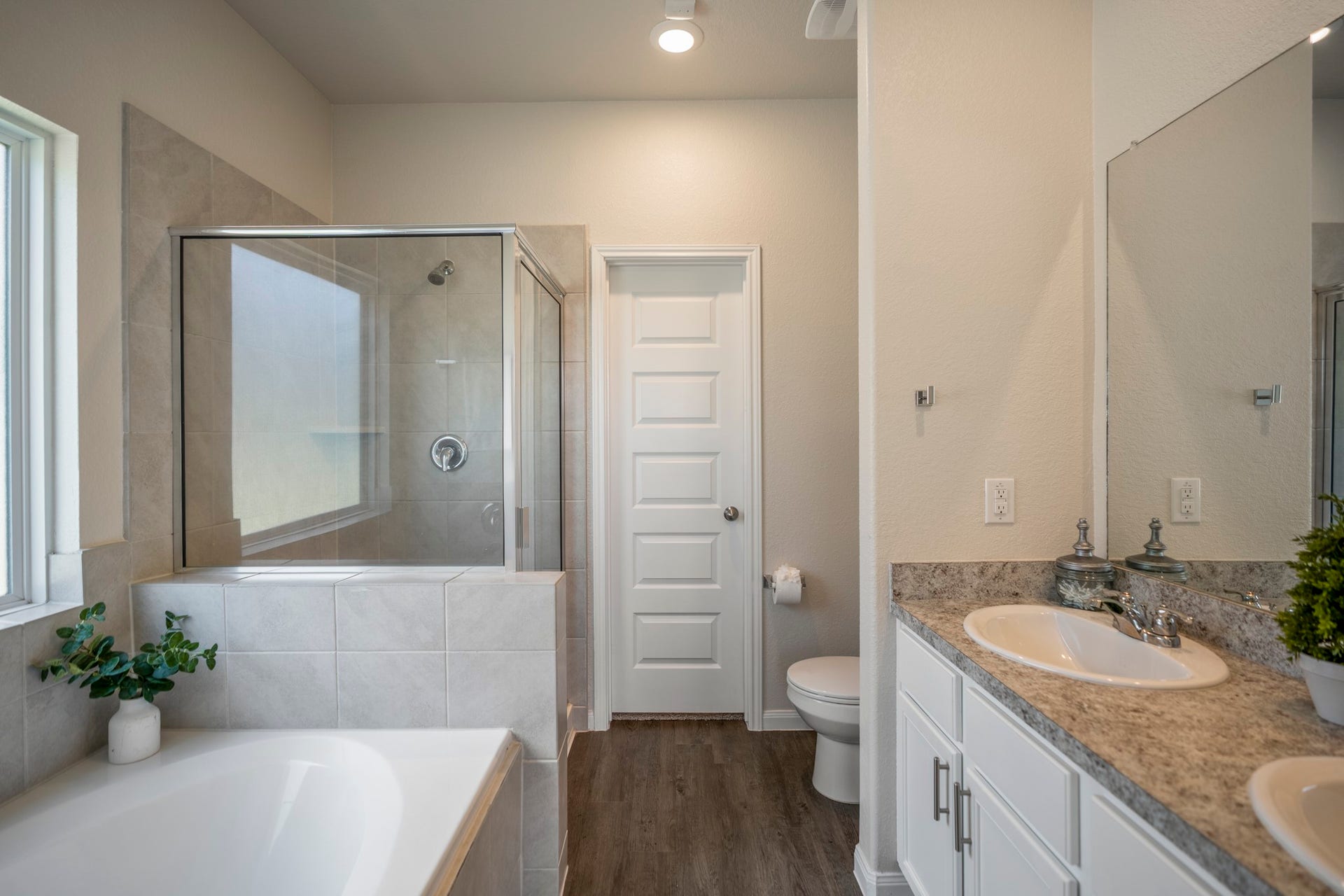 2355 Mount Locke Path, Conroe, TX 77301 Stepping into the primary bath, the separate soaking tub sits along the left with the glass-enclosed tile shower just beyond, while the vanity on the right offers dual sinks and plenty of everyday prep space. Straight ahead, the door leads into the oversized walk-in closetone of the standout storage features of the primary suite.
