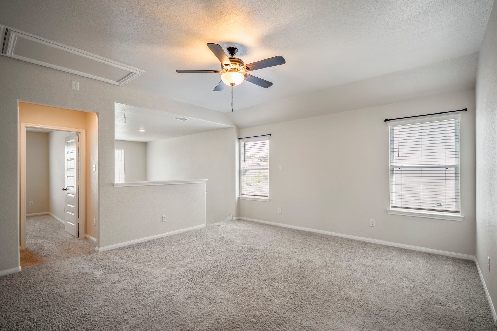 2355 Mount Locke Path, Conroe, TX 77301 At the top of the stairs, the home opens into a spacious gameroom with windows bringing in natural light from two sides. The doorway on the left leads into the first upstairs secondary bedroom.
