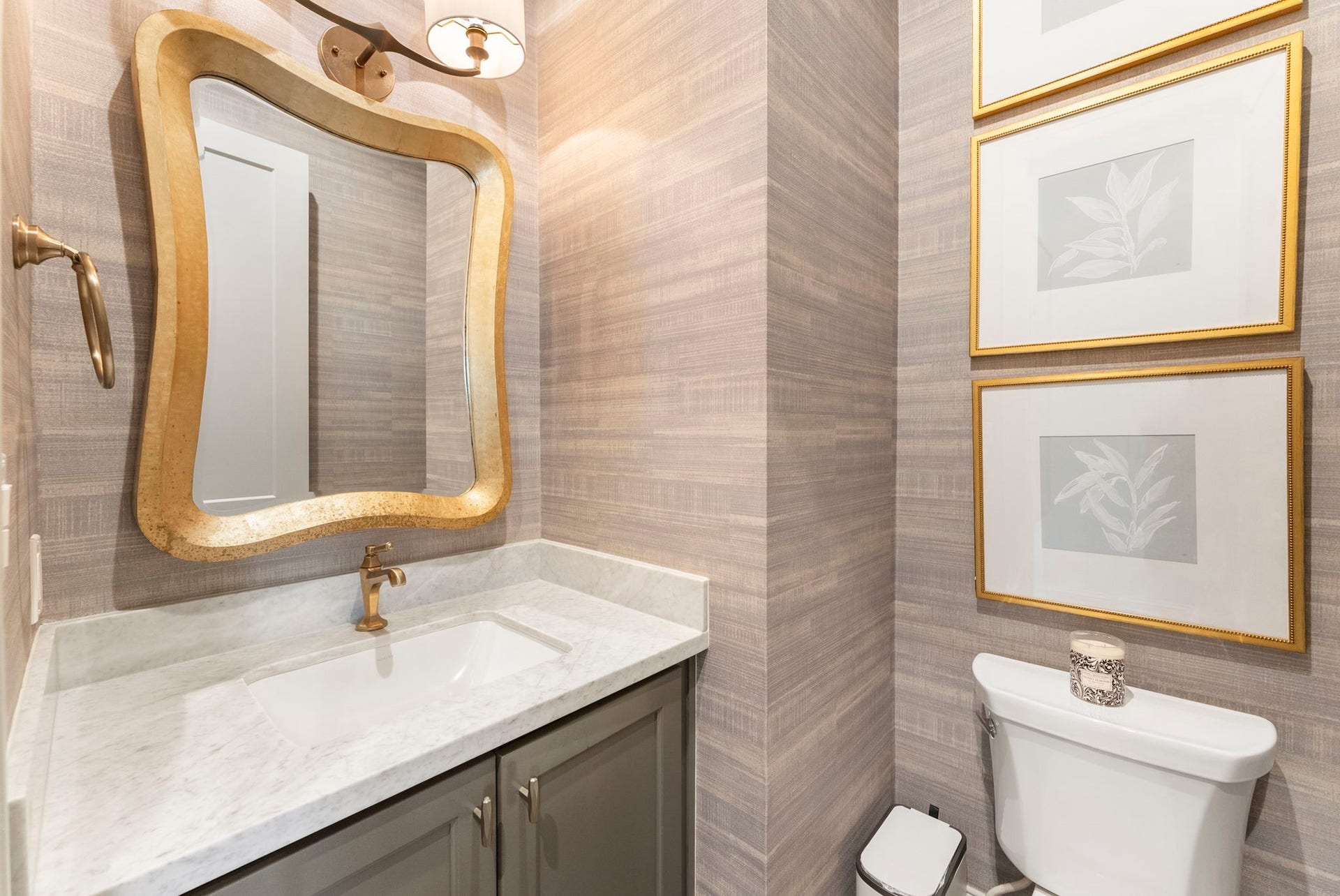10 Nautical Terrace Way, The Woodlands, TX 77380 Guest-ready powder room dressed in textured grasscloth-style paper, with marble vanity and brushed-gold fixtures that make a lasting impression.