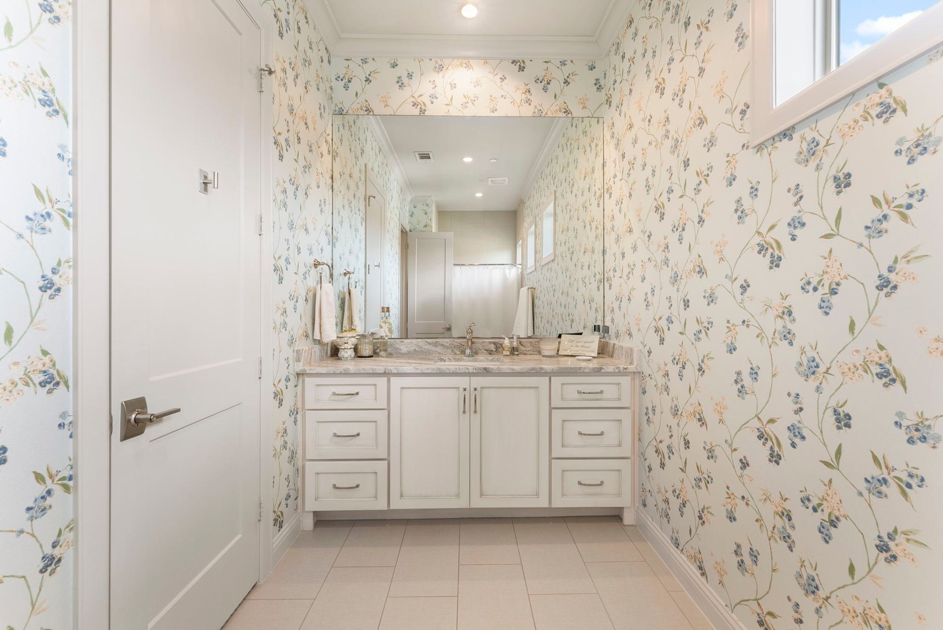 10 Nautical Terrace Way, The Woodlands, TX 77380 Fourth-floor bath shared by both guest bedrooms, featuring delicate floral wallpaper, a stone-topped vanity with abundant drawers, a separate bathing area and a clerestory window for natural light.