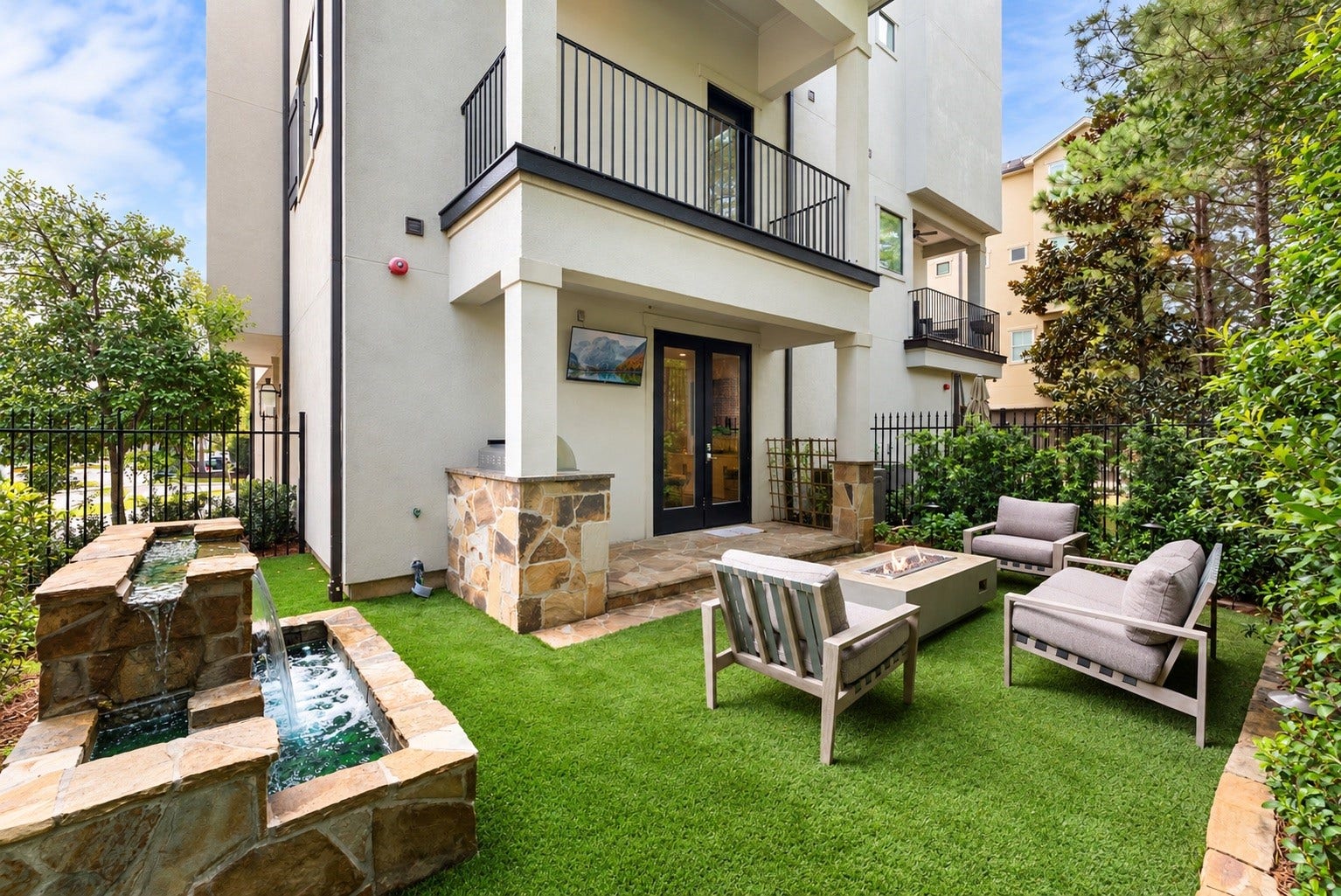 10 Nautical Terrace Way, The Woodlands, TX 77380 Rare fenced backyard, newly expanded with low-maintenance turf and fresh landscaping, anchored by a soothing stone water feature for a resort-like escape.
