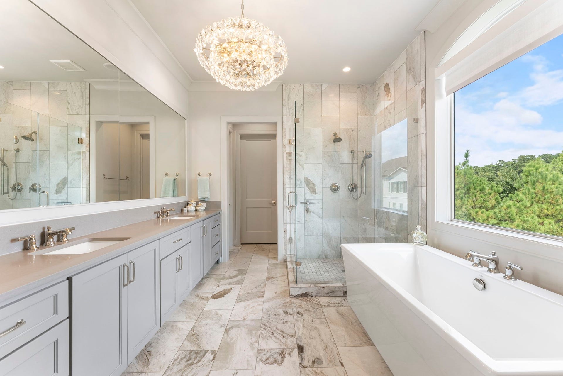 10 Nautical Terrace Way, The Woodlands, TX 77380 Marble spa bath with dual vanities, crystal chandelier, freestanding soaking tub and abundant natural light, a daily escape steps from the bedroom.