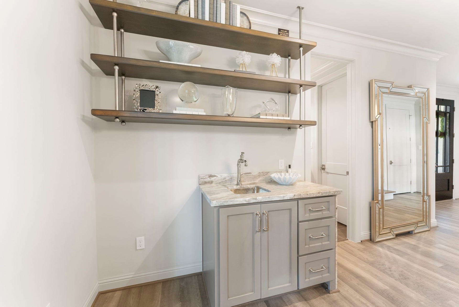 10 Nautical Terrace Way, The Woodlands, TX 77380 Convenient first-floor beverage station with hammered nickel sink, stone counter and open display shelving, perfect for hosting indoors or out.
