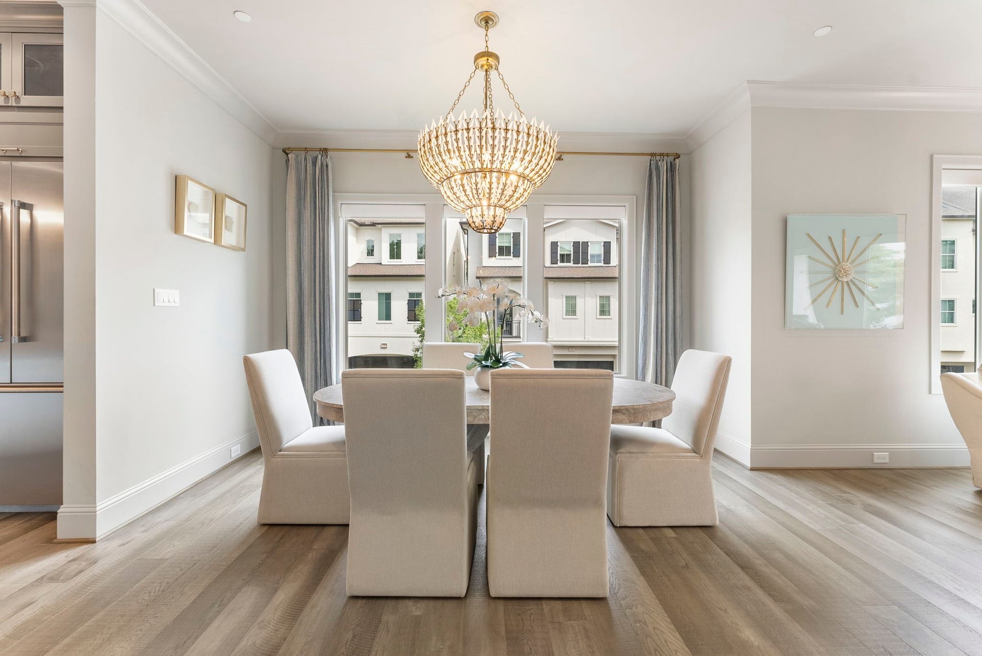 10 Nautical Terrace Way, The Woodlands, TX 77380 Formal dining framed by walls of windows and custom drapery, with a tiered gilded chandelier setting the tone for memorable dinners.