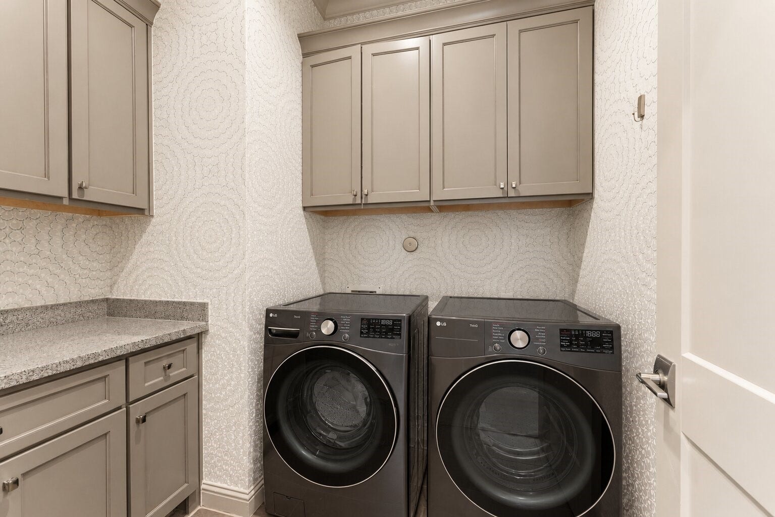 10 Nautical Terrace Way, The Woodlands, TX 77380 Thoughtfully placed on the primary-suite level, this utility room offers upper and lower cabinetry, a granite folding counter and charming patterned wallpaper, keeping laundry just steps from the closet.