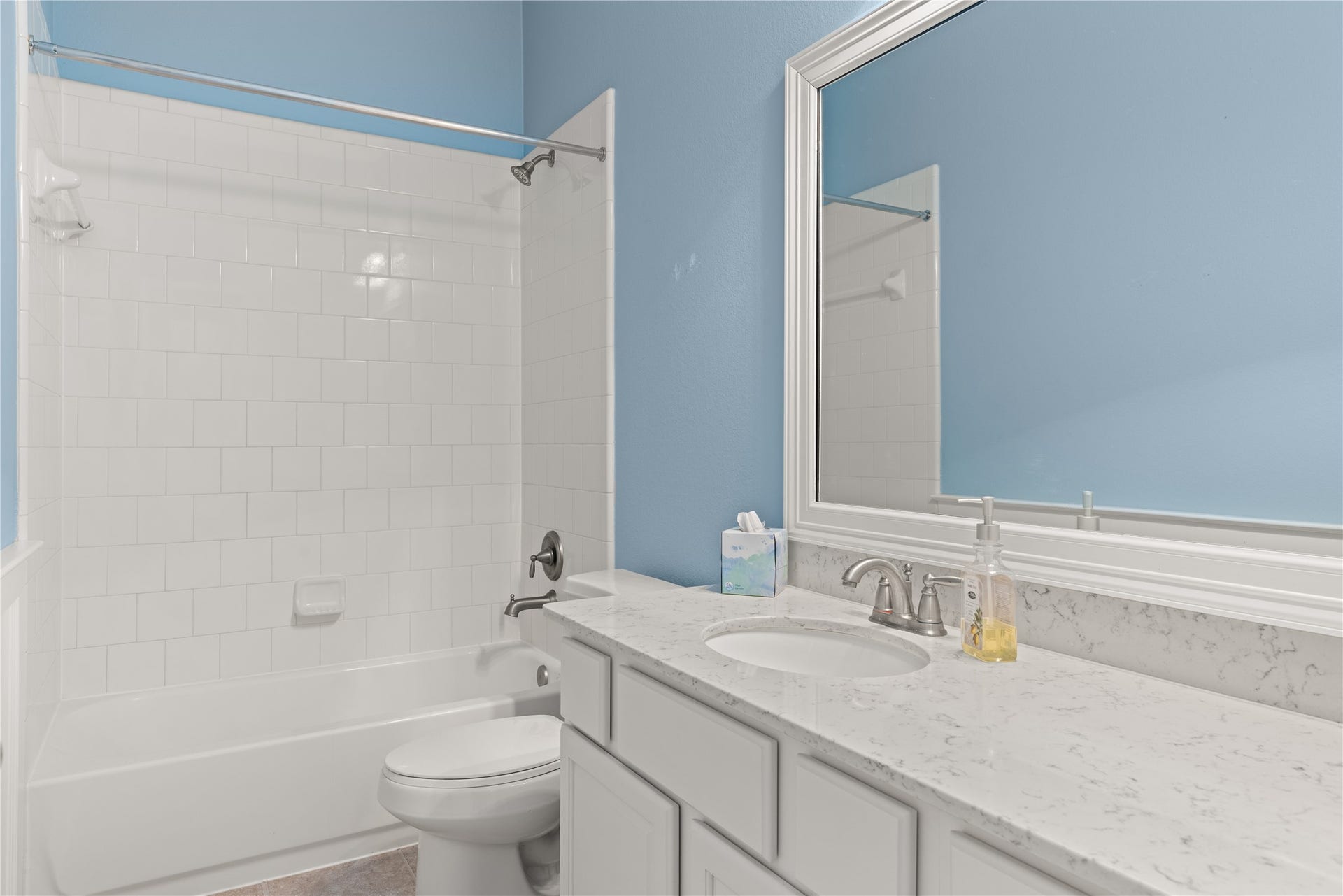 20507 Emery Manor Lane, Porter, TX 77365 Bright and inviting jack and jill bathroom featuring a sleek white vanity with a marble countertop, an elegant mirror, and a pristine bathtub with classic tile surround.