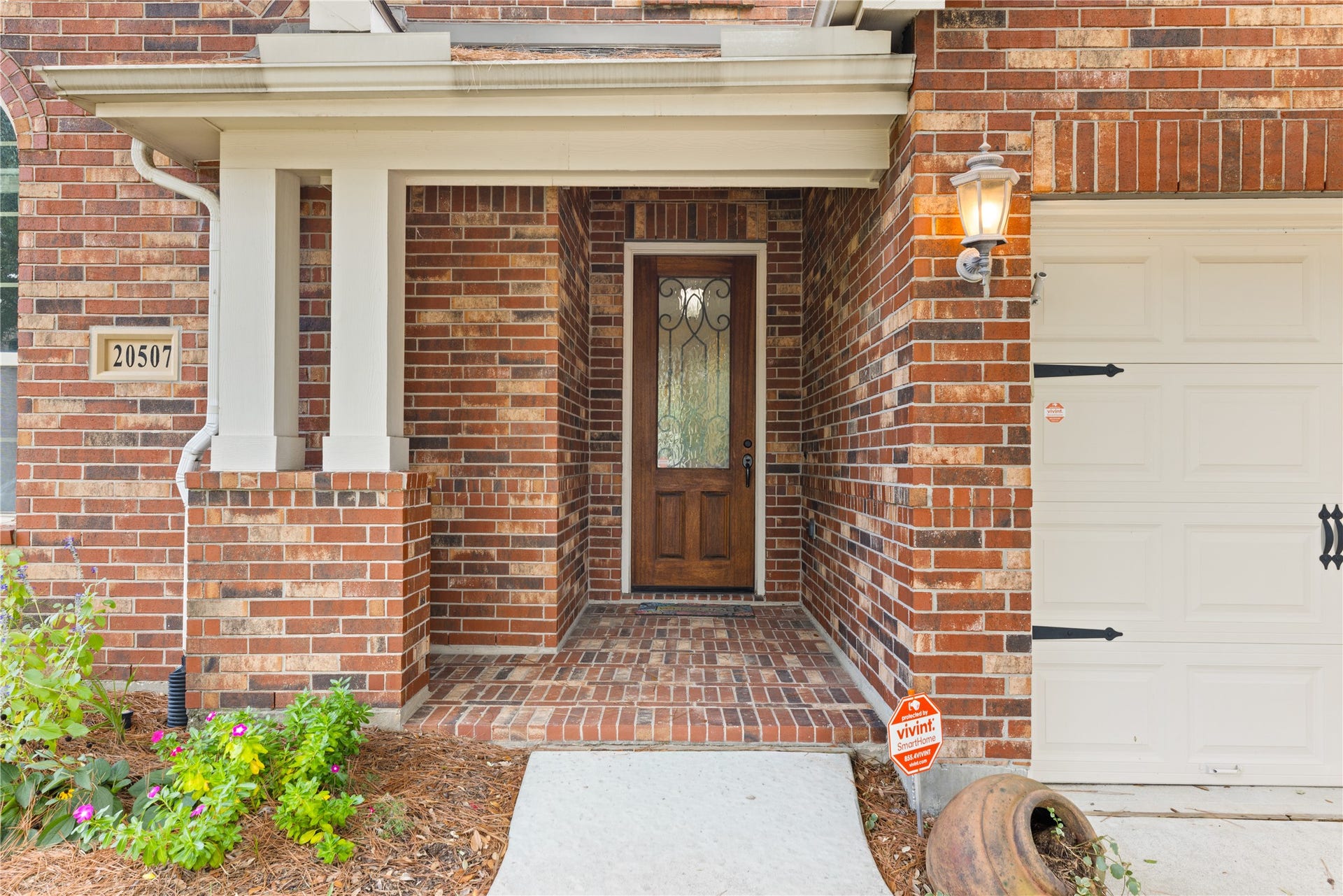20507 Emery Manor Lane, Porter, TX 77365 Charming brick entryway with a decorative glass front door, complemented by a classic lantern light and tasteful landscaping.