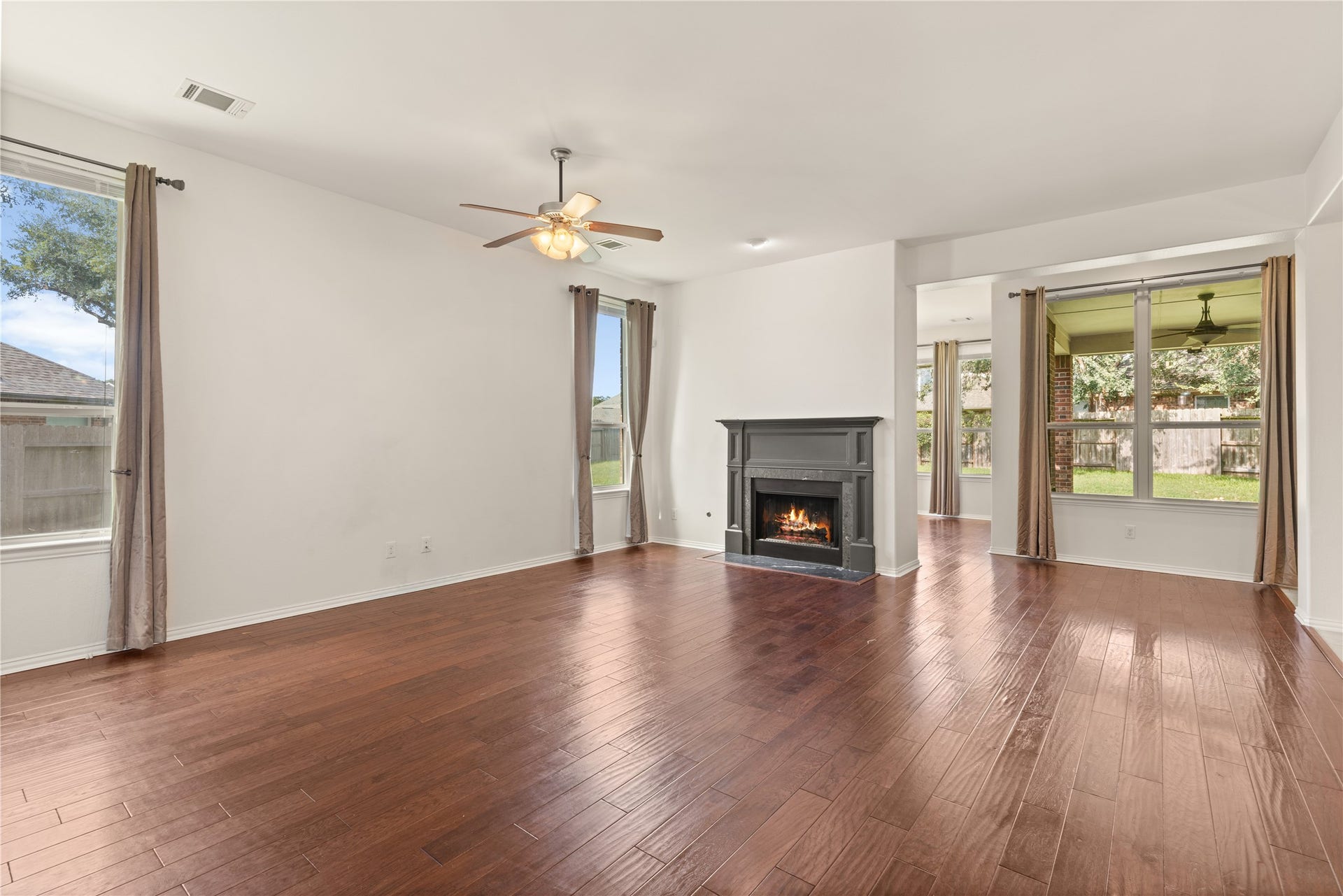 20507 Emery Manor Lane, Porter, TX 77365 Spacious living area featuring rich hardwood floors, a cozy fireplace, and abundant natural light from large windows overlooking the backyard.