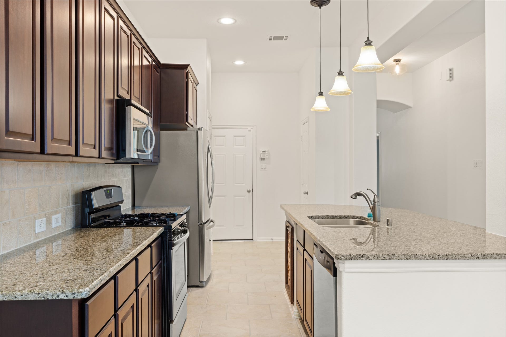 20507 Emery Manor Lane, Porter, TX 77365 Modern kitchen with granite countertops, stainless steel appliances, and rich wood cabinetry, enhanced by elegant pendant lighting.