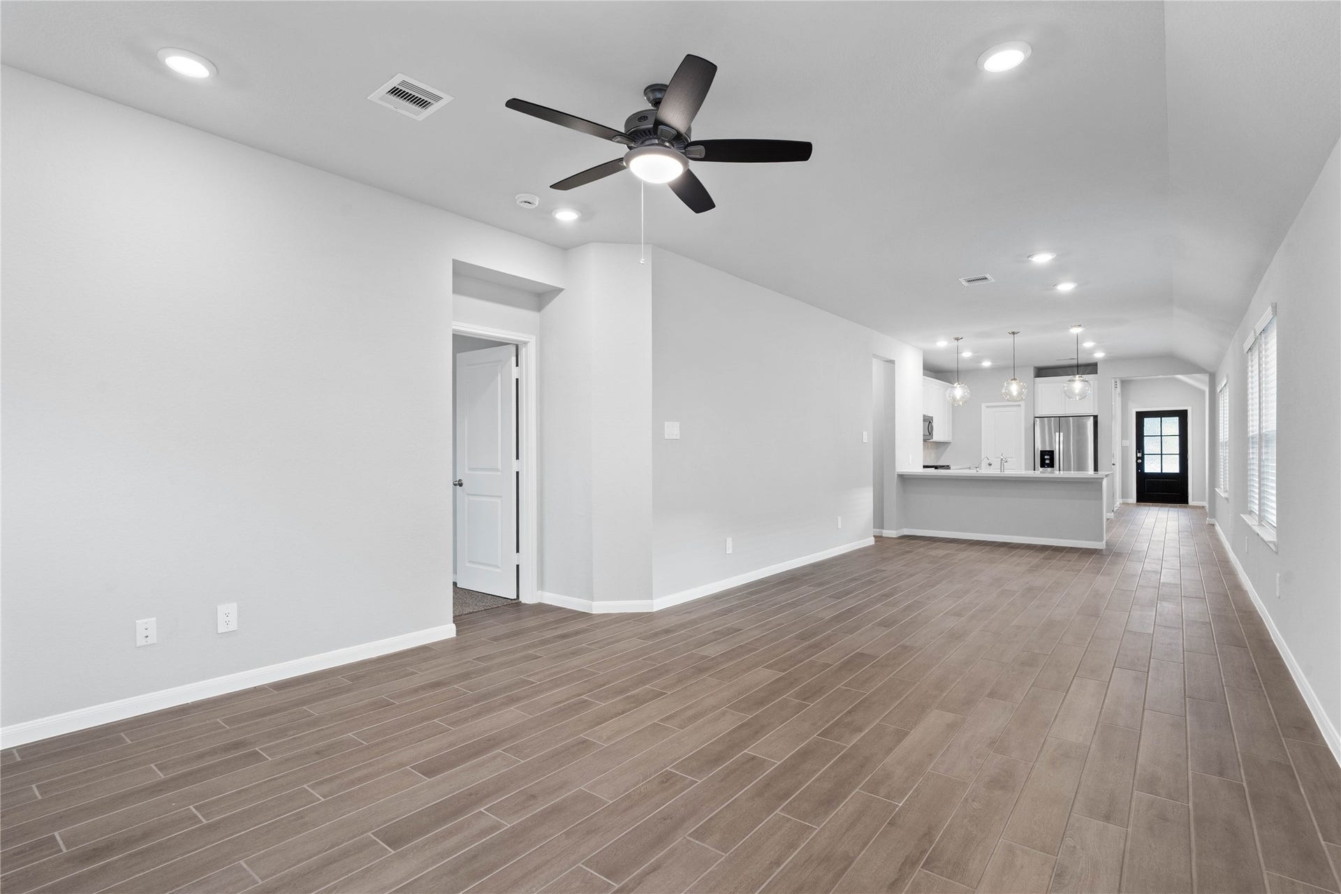 19560 Stripe Hill Bend, Montgomery, TX 77316 This expansive view from the back of the house showcases a seamless, open-concept layout that creates a warm and inviting path for guests, drawing the eye past the heart of the home toward the welcoming front entryway