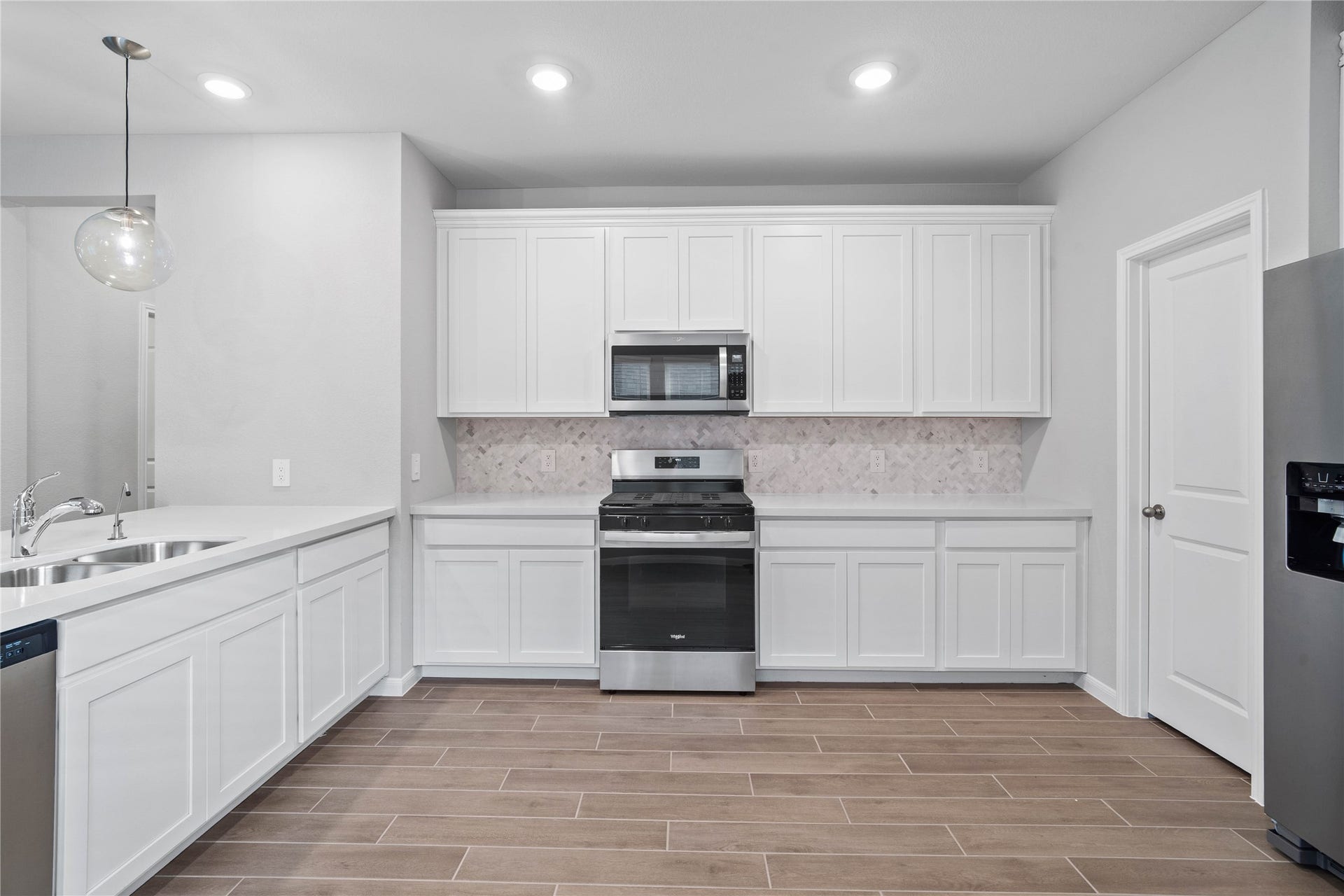 19560 Stripe Hill Bend, Montgomery, TX 77316 Expansive countertops provide a clean, horizontal sweep that beautifully highlights the intricate patterns of the Mosaix Daphne White Herringbone backsplash.