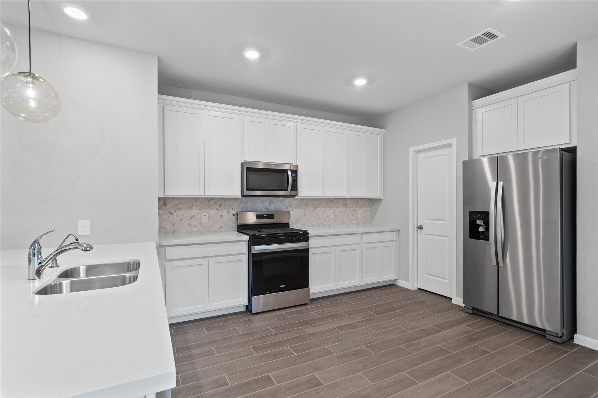 19560 Stripe Hill Bend, Montgomery, TX 77316 Discover this chef-ready kitchen featuring sleek, white shaker-style cabinetry, frost white quartz countertops, and a full suite of stainless steel appliances, including an over-the-range microwave and a side-by-side refrigerator.