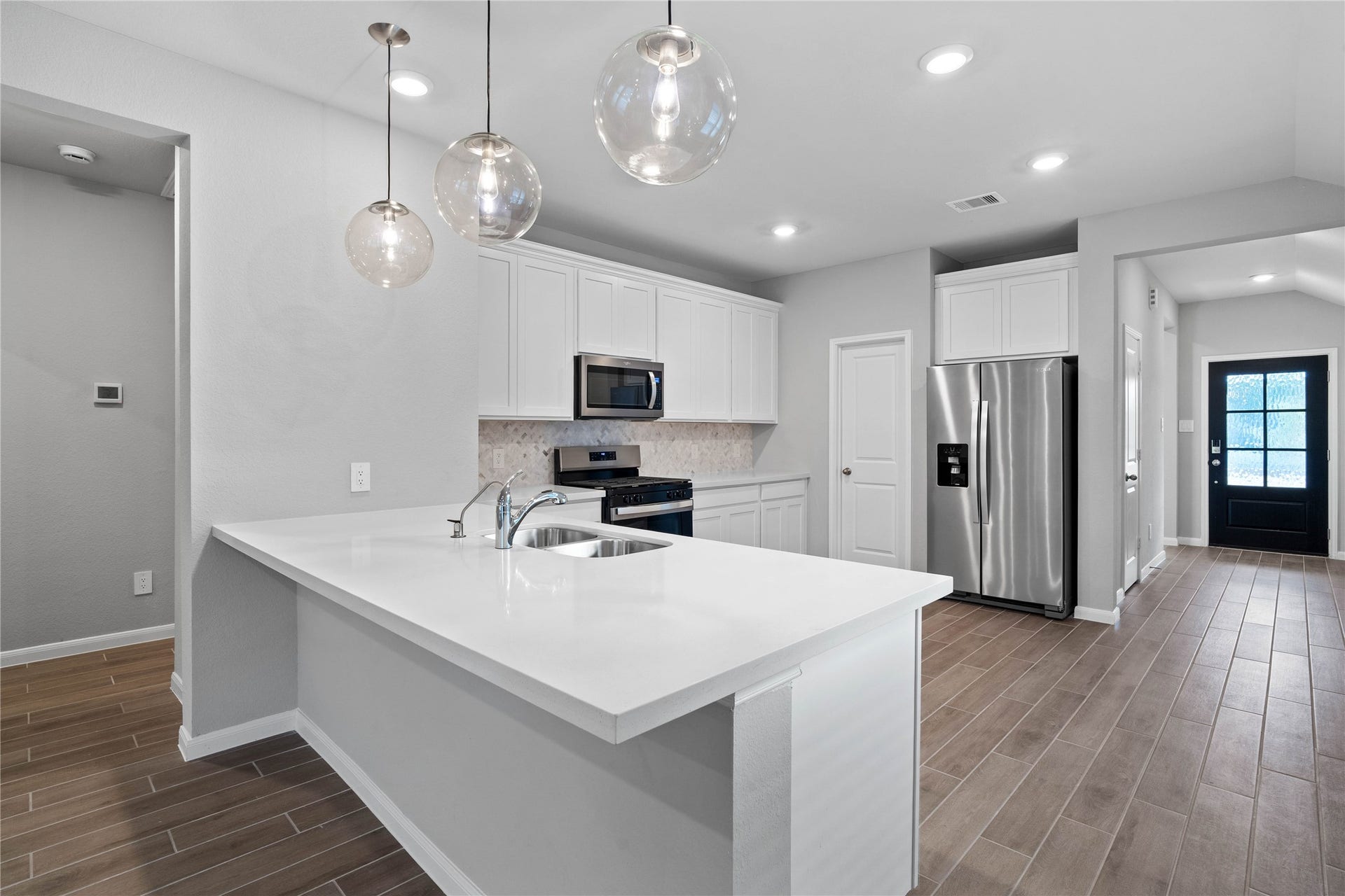 19560 Stripe Hill Bend, Montgomery, TX 77316 As you step past the entryway, you are immediately welcomed by a bright, open-concept kitchen that serves as the home's focal point. The space feels clean and modern, anchored by a large quartz-topped kitchen counter that seamlessly connects the cooking area to a long, light-filled living space.