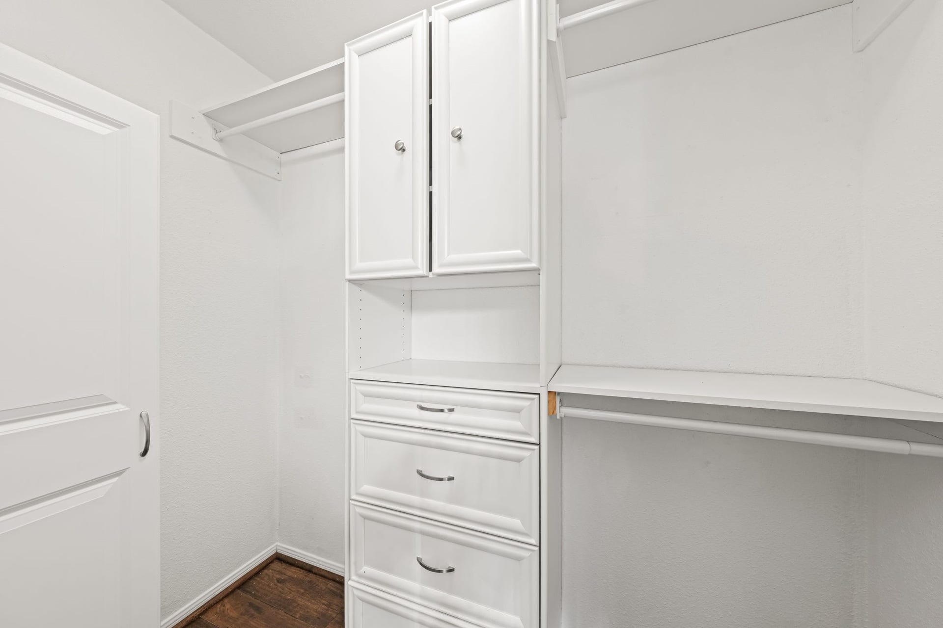 2211 S Kirkwood Road, #1, Houston, TX 77077 The primary walk-in closet is fully built out a white painted cabinetry system runs floor to ceiling with enclosed upper cabinets, open adjustable shelving, a three-drawer built-in dresser column, and hanging rods on both walls. No wire shelving, no improvised storage. It arrives organized.