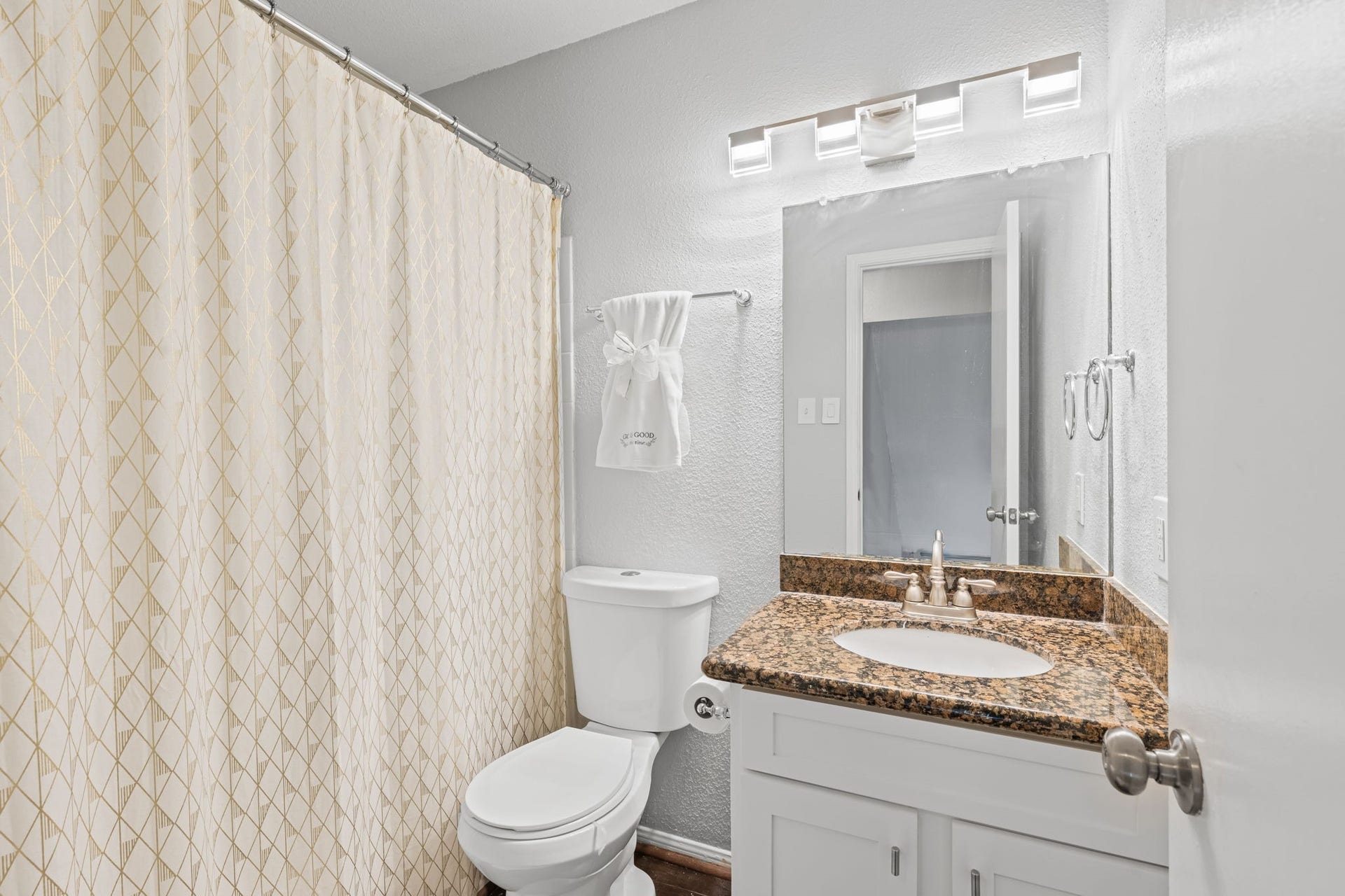 2211 S Kirkwood Road, #1, Houston, TX 77077 The secondary bath carries the same dark speckled granite countertop as the kitchen and primary bath a consistent finish language that runs through every wet space in the unit. A tub/shower combination occupies the left wall, and a modern rectangular light bar above the mirror keeps the space well lit.