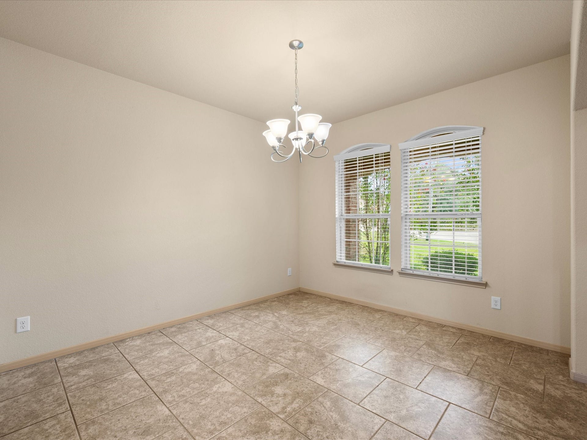 Versatile formal dining room located off the main entry, complete with a traditional light fixture, tile flooring, and large windows with blinds for great natural lighting. Perfect as a dedicated dining space or a home office/study.