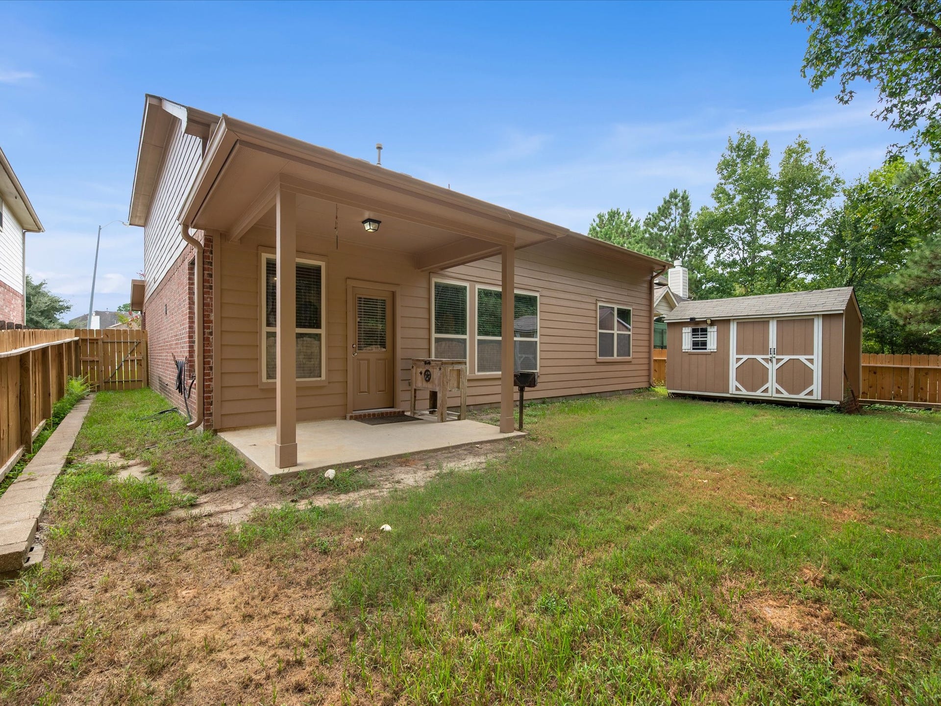 Rear exterior featuring a covered patio, fully fenced lawn, detached storage shed, and private backyard setting with no rear neighbors.