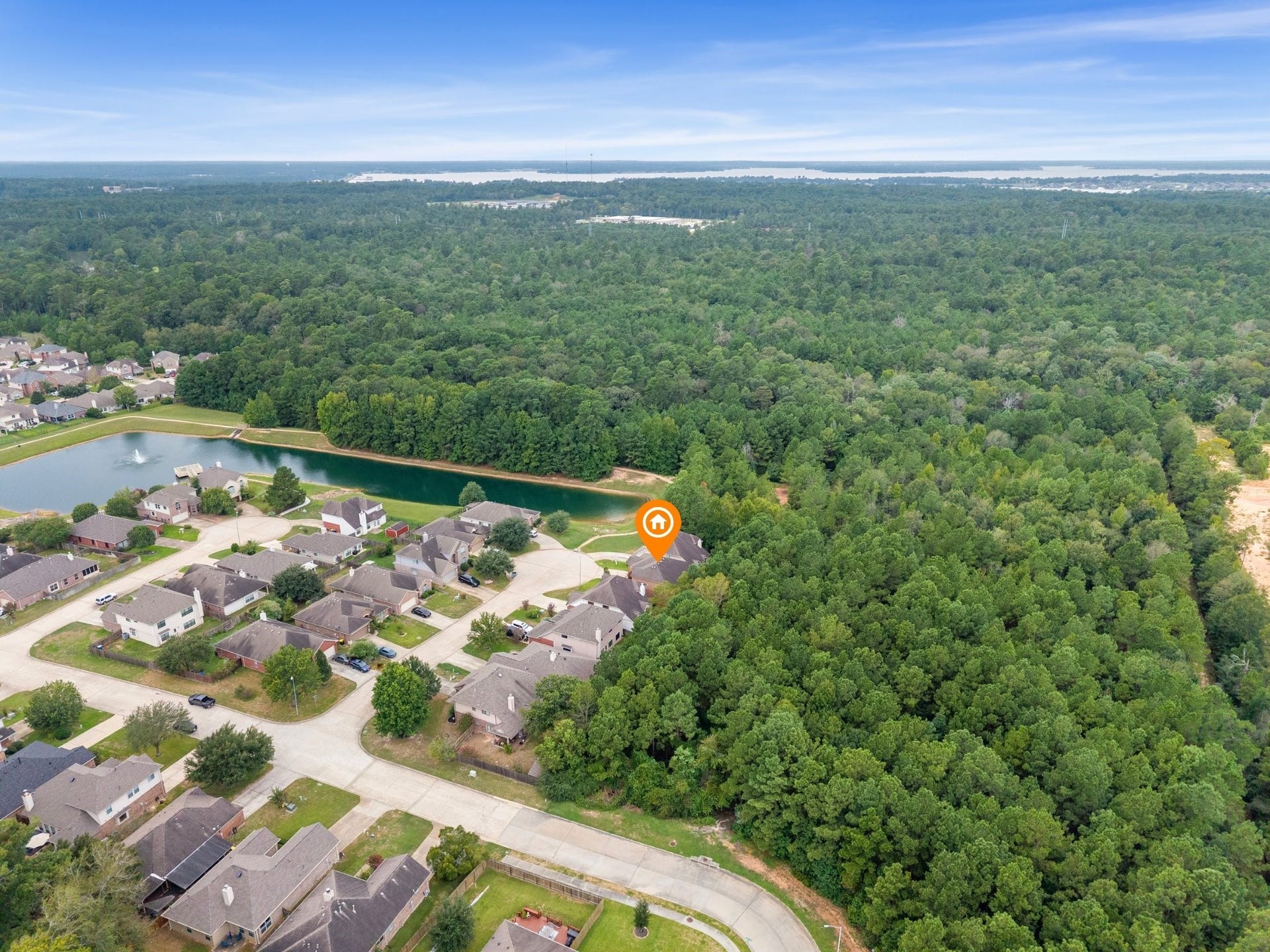 Wide aerial view illustrating the property's incredible privacy against a dense forest reserve, steps from the neighborhood lake, and within close proximity to Lake Conroe.