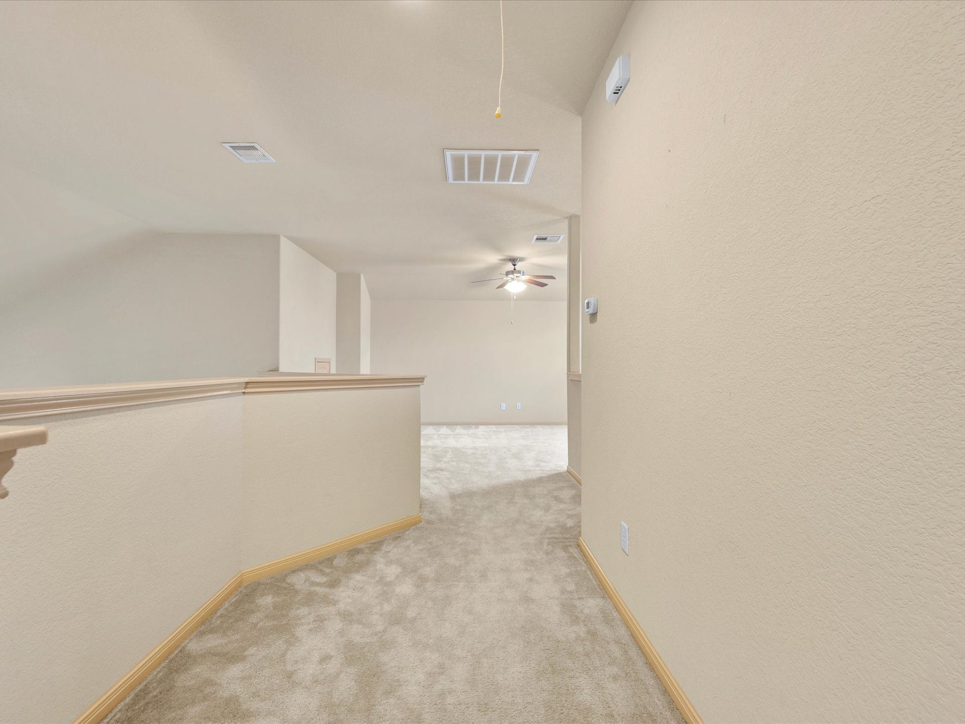 Upper-level hallway and landing with plush carpeting and soaring ceilings, offering seamless flow between secondary bedrooms and the expansive second living room.