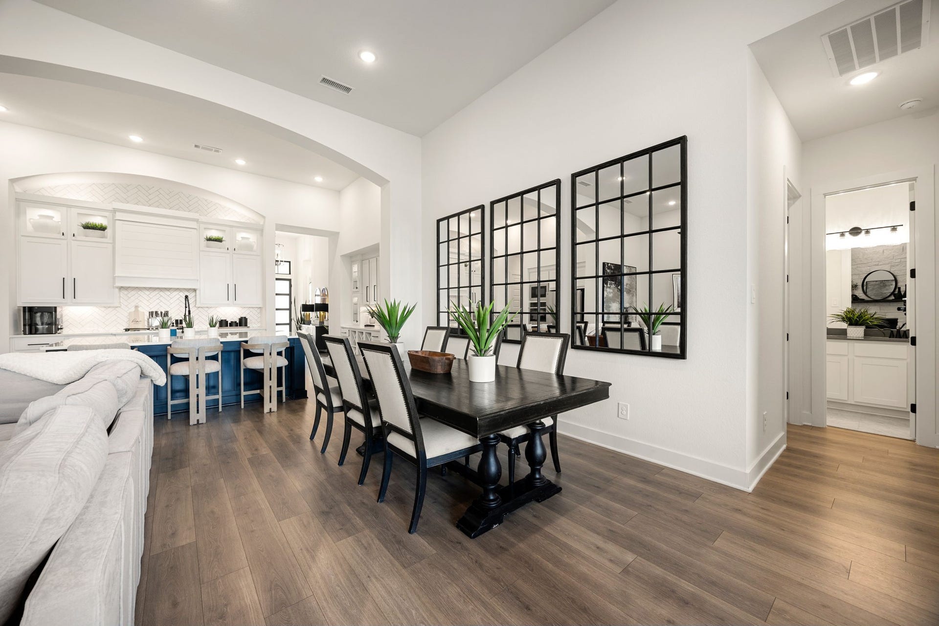31322 Crescent Hill Drive, Fulshear, TX 77441 An effortlessly connected layout. The elegant dining space transitions seamlessly into both the gourmet kitchen and the main living area, highlighted by wide-plank flooring, clean lines, recessed lighting, and a view into a private hallway nook.