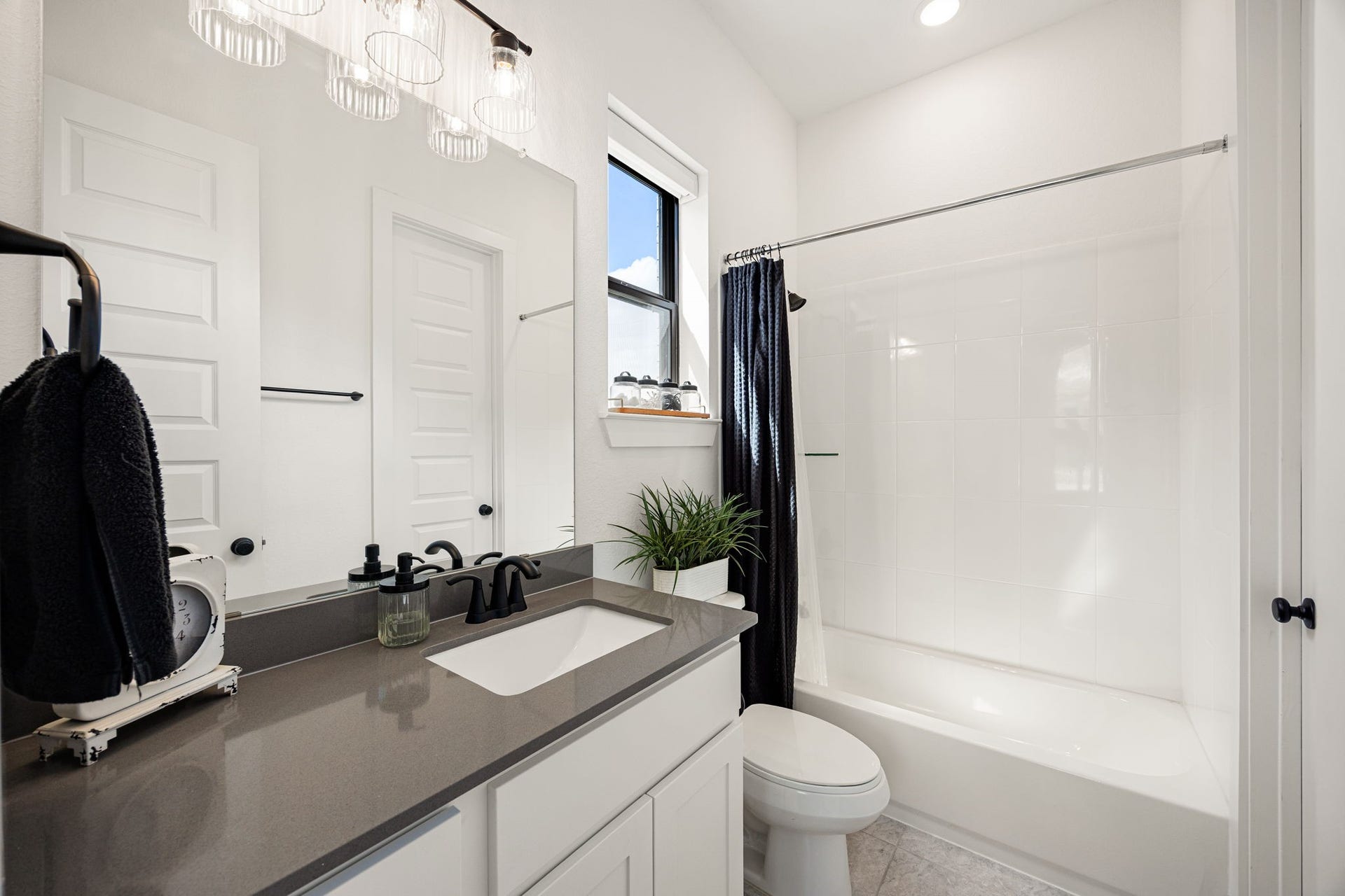 31322 Crescent Hill Drive, Fulshear, TX 77441 Immaculate and modern secondary bath. Crisp white cabinets contrast beautifully with premium grey countertops, an undermount sink, matte black hardware, custom vanity lighting, and a clean tub-and-shower combo.