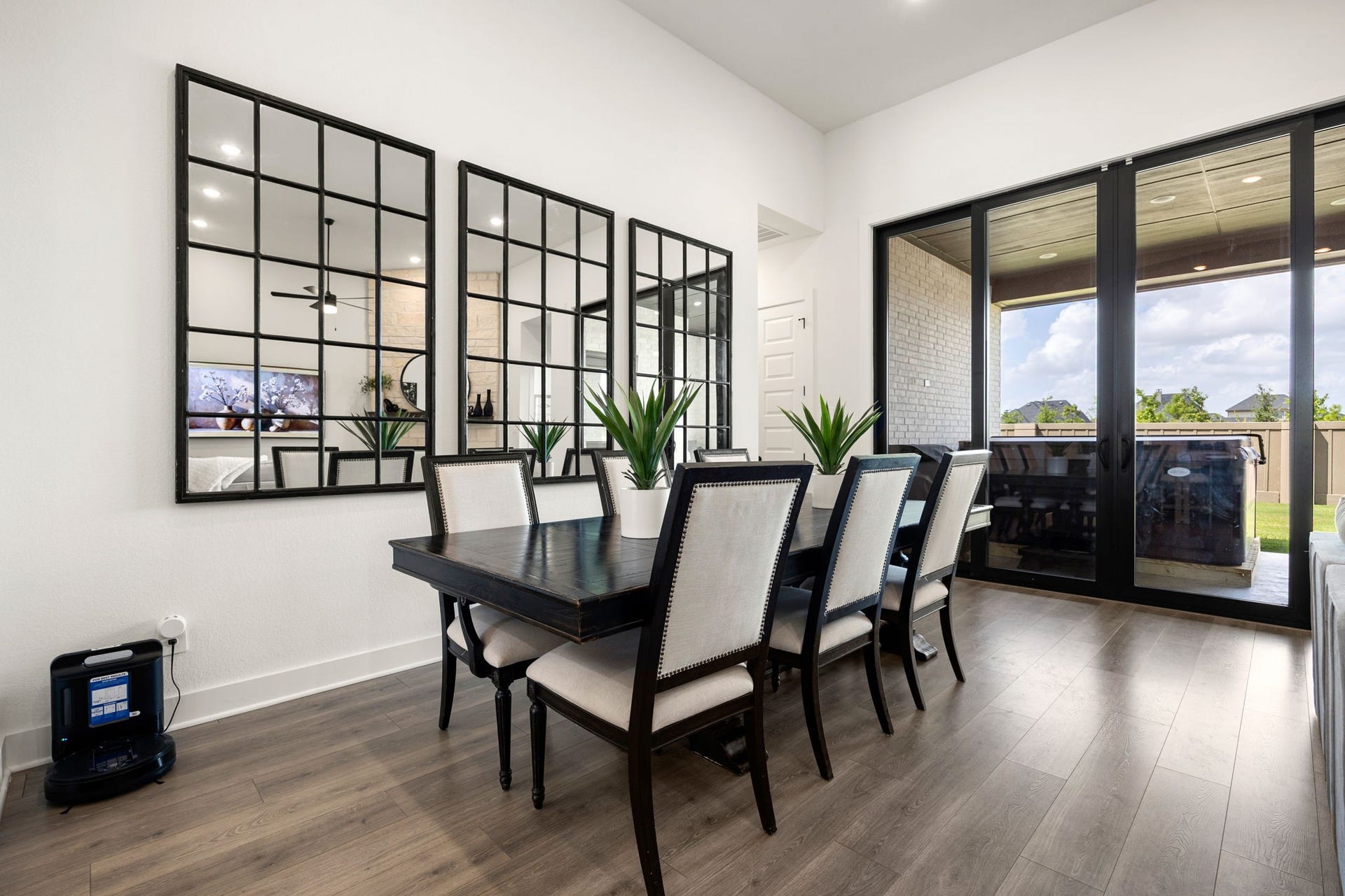 31322 Crescent Hill Drive, Fulshear, TX 77441 Bright and airy dining experience. Expansive wall-to-wall black glass sliders flood the room with natural light and lead out to a covered patio, beautifully showcasing the home's high-end wide-plank flooring, crisp white walls, and towering ceilings.
