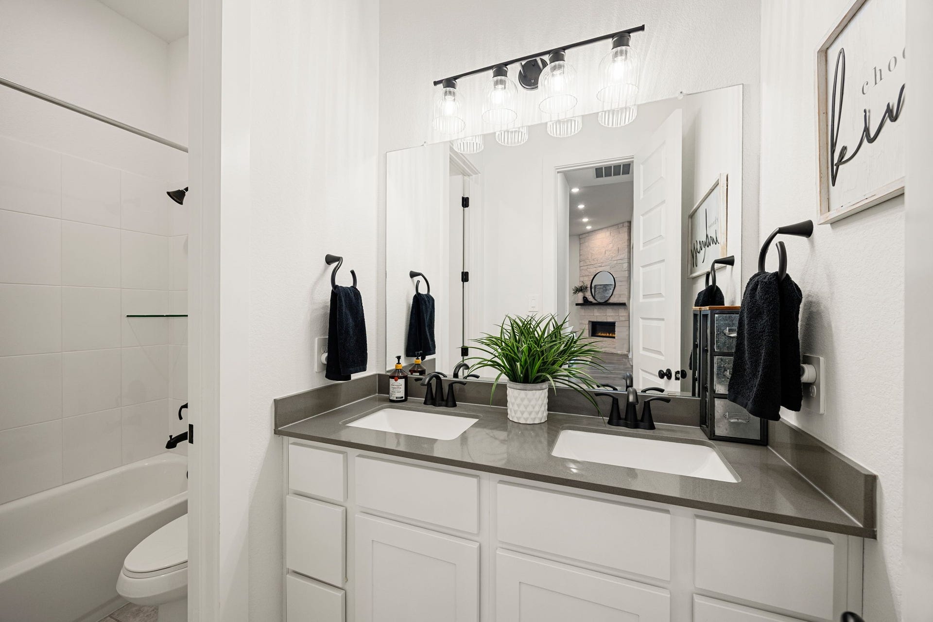 31322 Crescent Hill Drive, Fulshear, TX 77441 A crisp and functional secondary bath. White shaker-style cabinetry is paired with premium grey countertops, dual undermount rectangular sinks, matte black fixtures, modern vanity lighting, and a clean tub-and-shower combination.