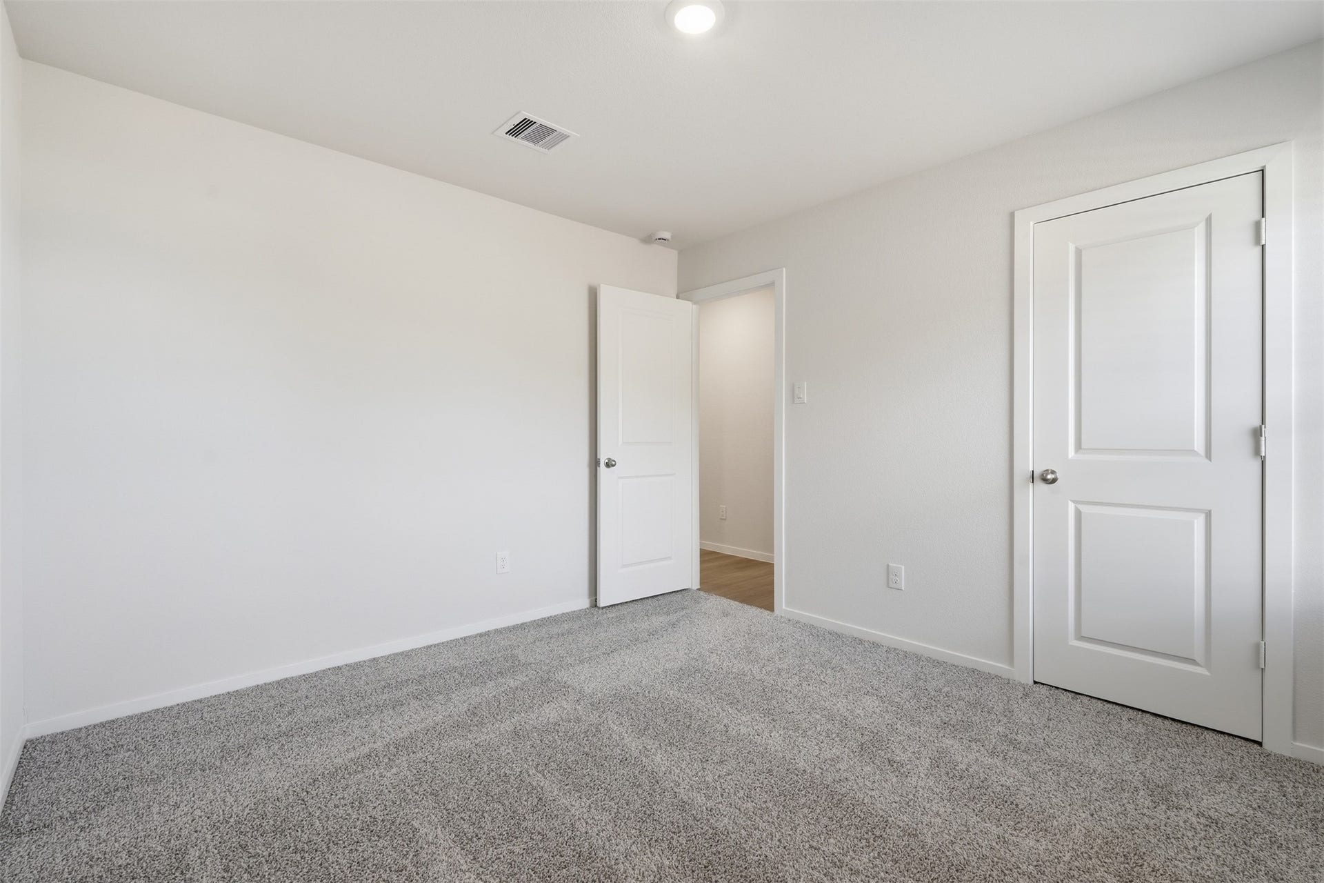Bright and inviting bedroom featuring plush carpeting, neutral walls, and ample closet space, perfect for a cozy retreat.