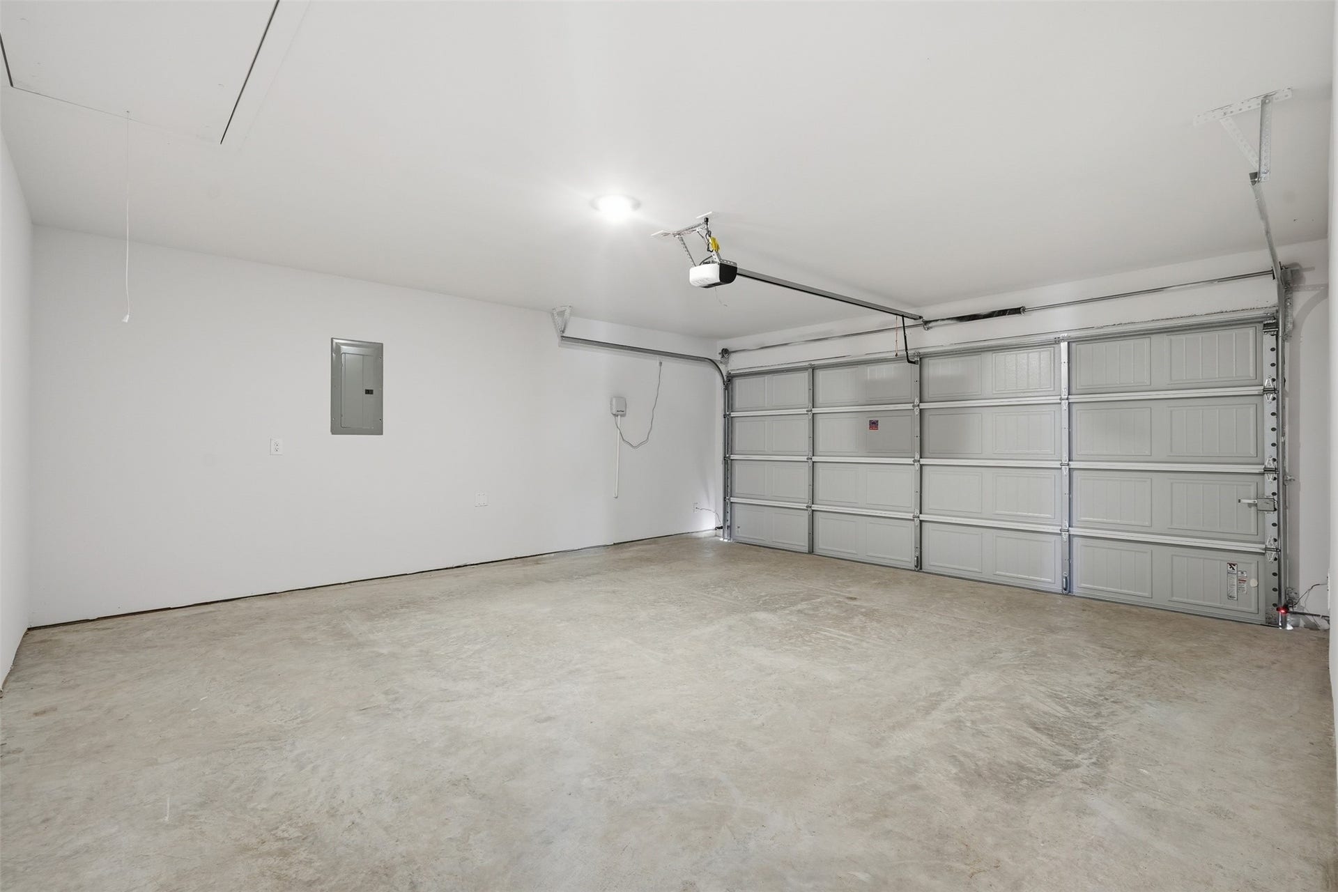 Spacious and clean two-car garage with concrete flooring and ample lighting, perfect for storage or workshop potential.