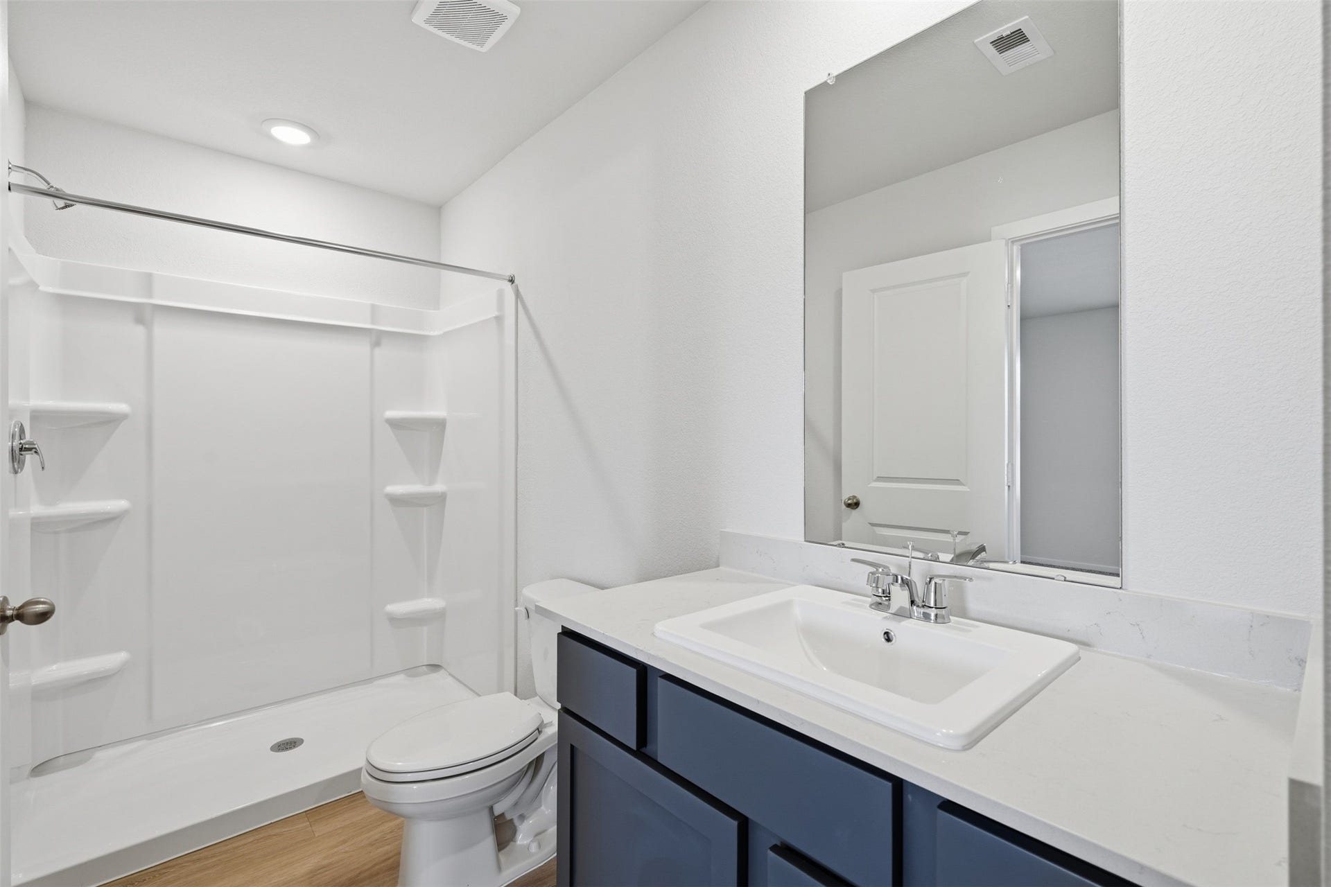 Modern bathroom featuring a sleek shower with built-in shelving, a stylish vanity with a large mirror, and elegant fixtures.