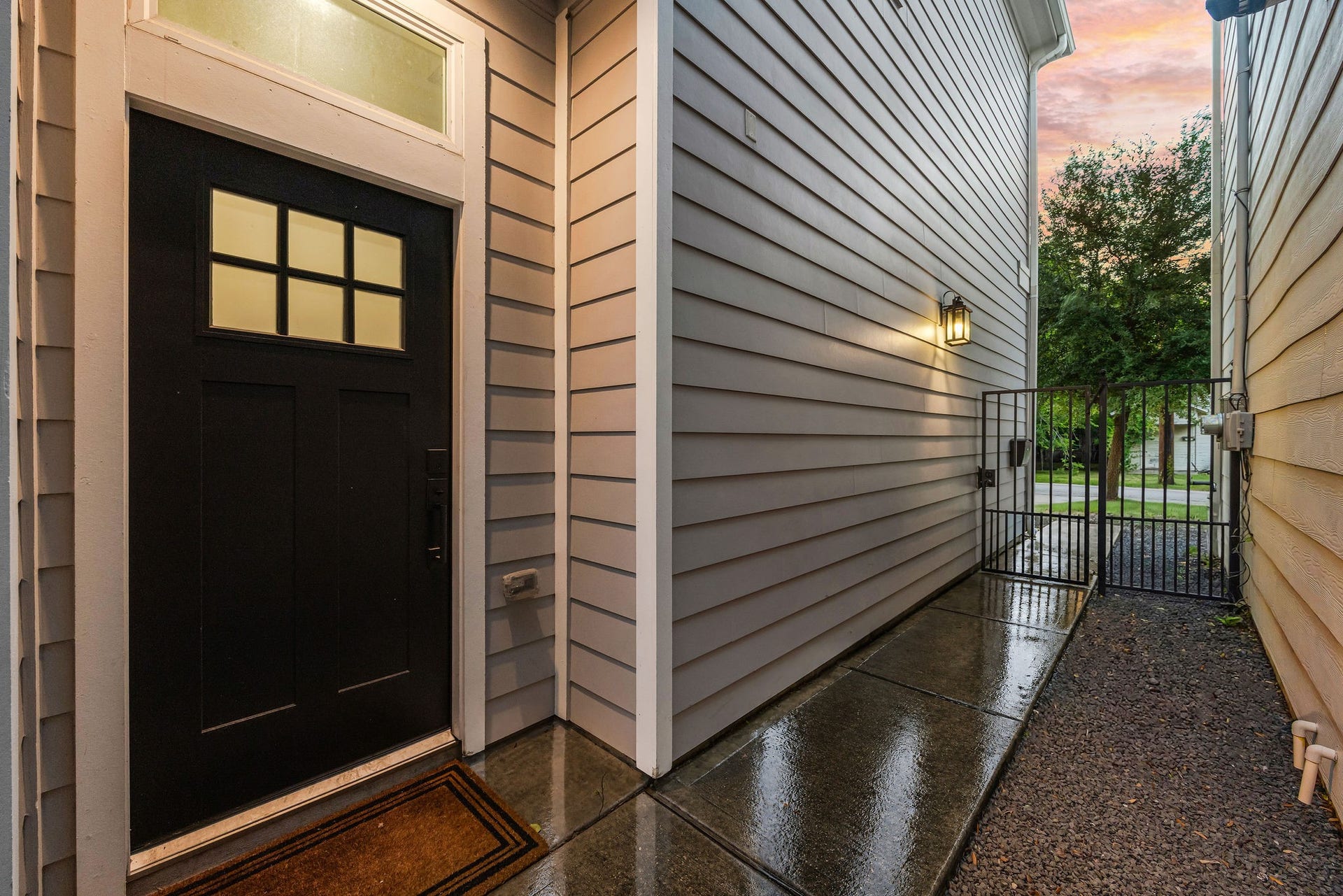 5537 Petty Street, Houston, TX 77007 Inviting entryway with a modern black door, elegant side lighting, and a secure gate leading to a peaceful outdoor space.