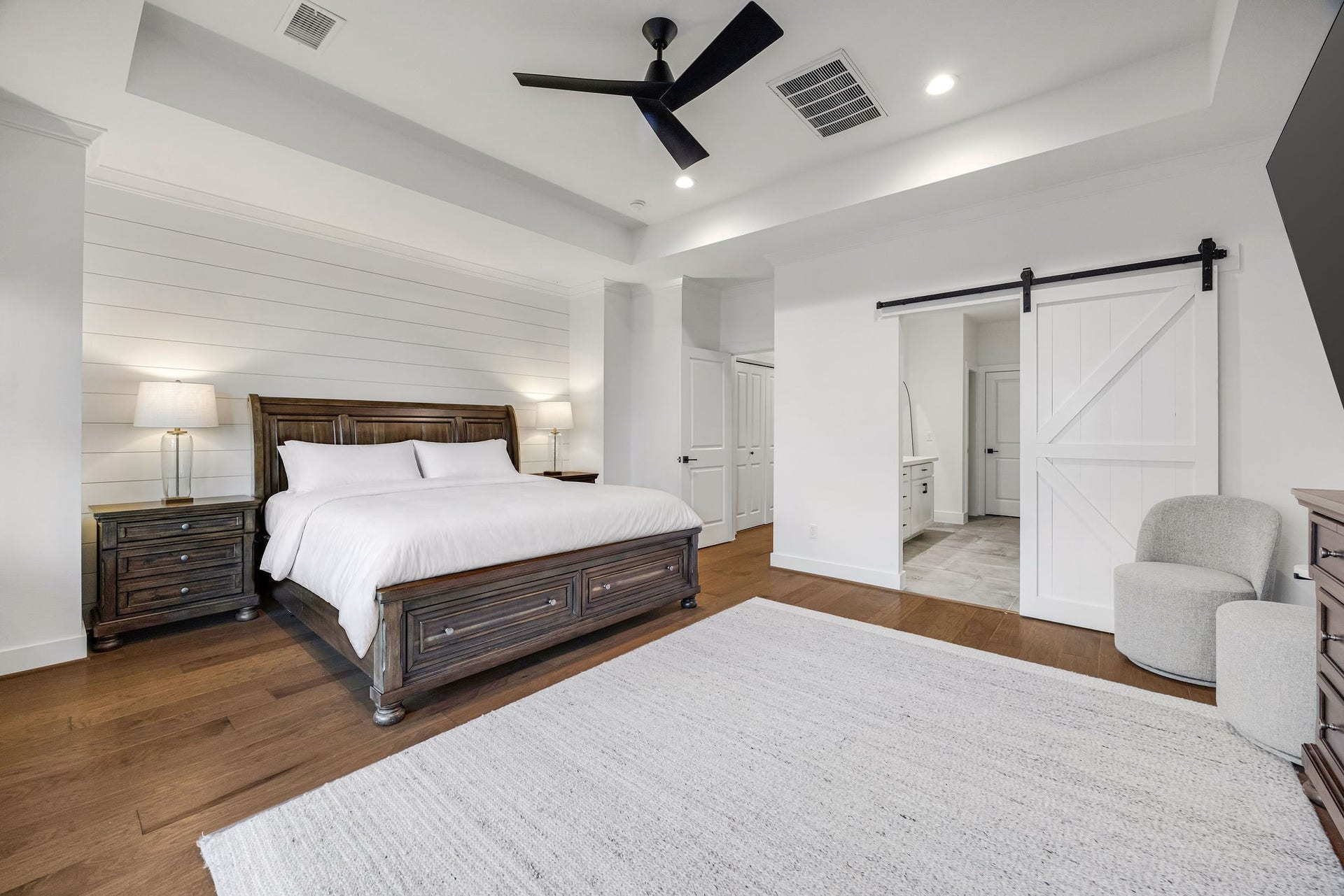 5537 Petty Street, Houston, TX 77007 Spacious primary bedroom features elegant shiplap accent wall, and sleek barn door leading to a bright en-suite bathroom.