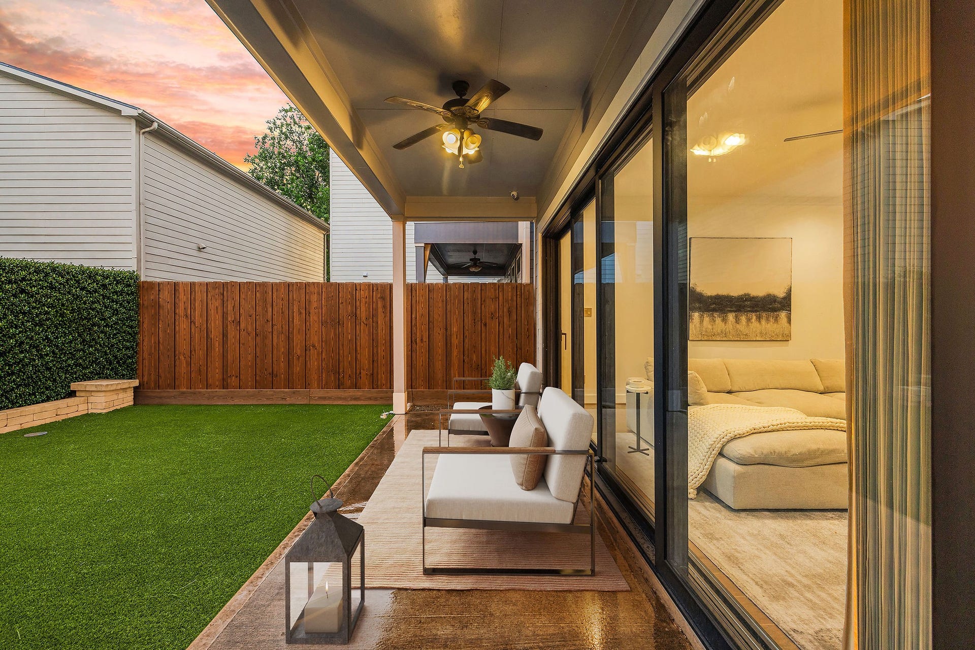5537 Petty Street, Houston, TX 77007 Charming covered patio with ceiling fan and comfortable seating, seamlessly connecting to a cozy indoor living space through sliding glass doors, all overlooking a low-maintenance artificial turf yard.