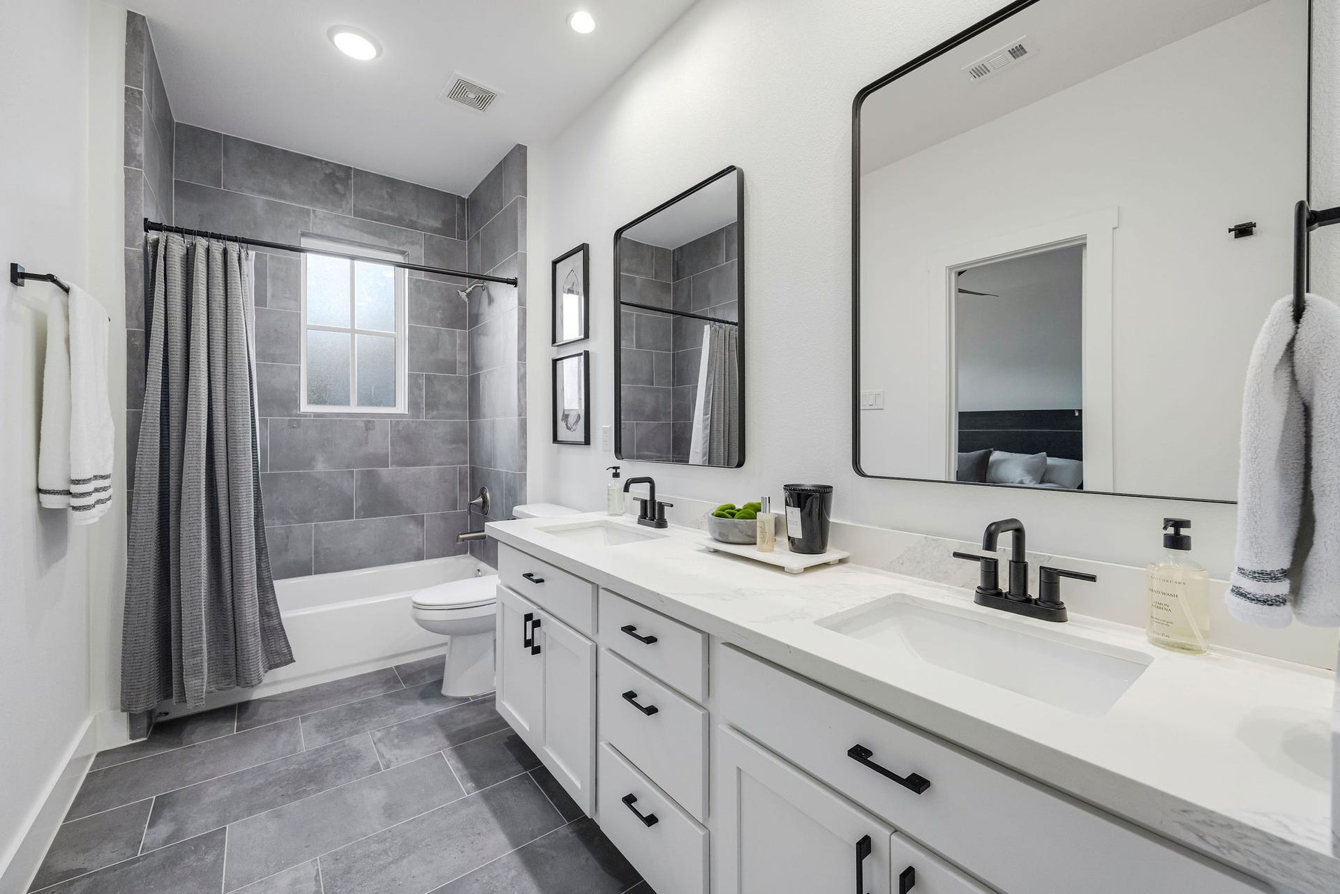5537 Petty Street, Houston, TX 77007 Sleek and modern bathroom featuring dual sinks with elegant black fixtures, a spacious vanity, and a stylish tub-shower combo with gray tile accents.