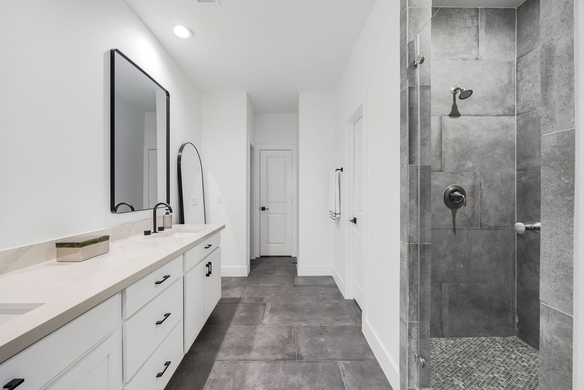 5537 Petty Street, Houston, TX 77007 Elegant en-suite bathroom featuring a spacious walk-in shower with sleek gray tiles, a long vanity with dual sinks, and modern fixtures.