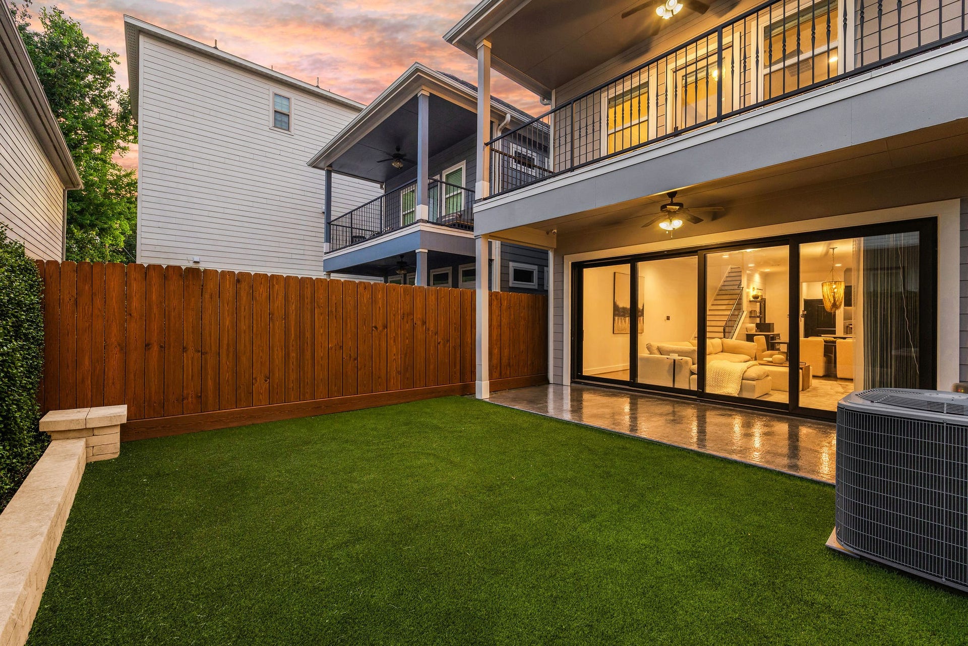 5537 Petty Street, Houston, TX 77007 Spacious backyard with lush artificial turf and a sleek patio, perfect for outdoor entertaining, featuring seamless indoor-outdoor flow through large sliding glass doors.